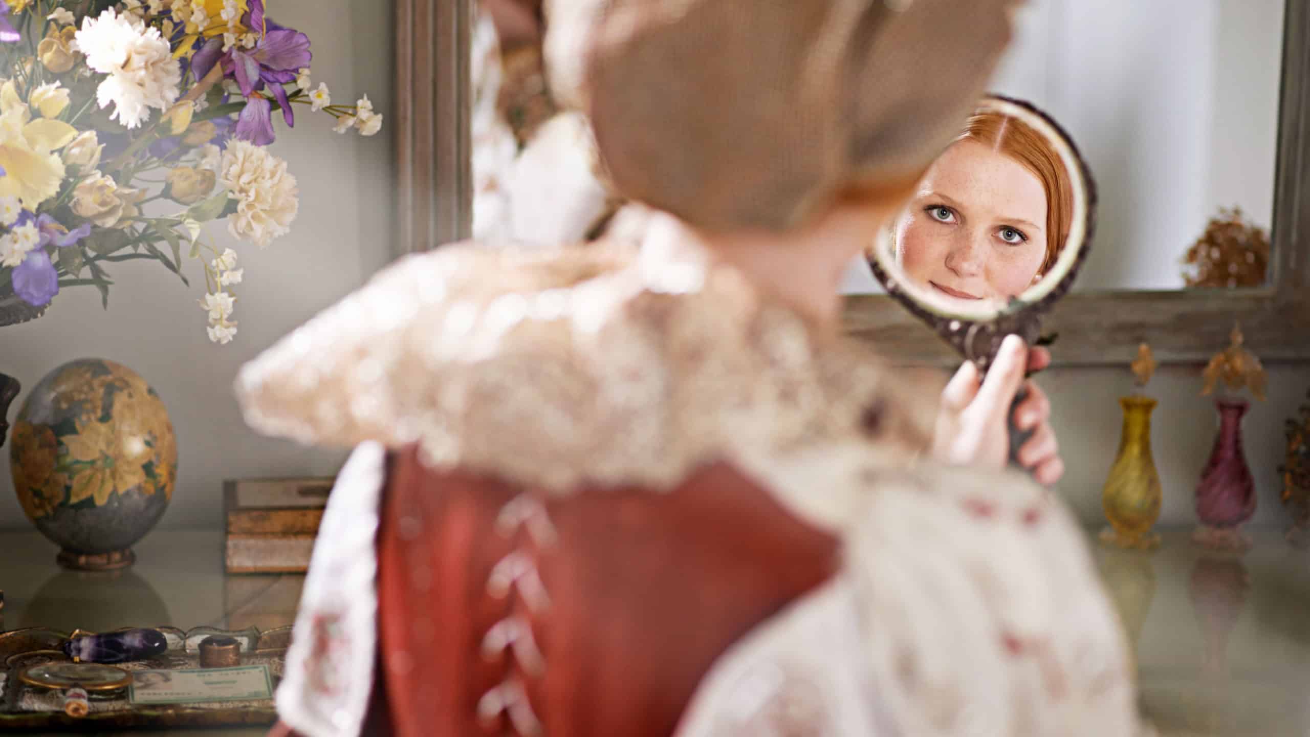 Reflection, mirror and woman with renaissance, medieval and classic style in a palace bedroom. Luxury, mansion and beauty skincare routine in a home with vintage fashion and care of a queen and ruler