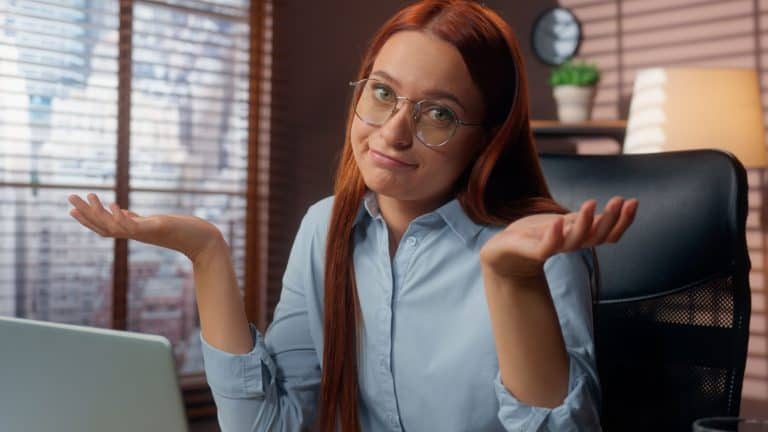 Business woman businesswoman in office working laptop online problem difficult Caucasian female girl shrug shoulders unsure trouble employer manager using computer looking at camera specialist failure