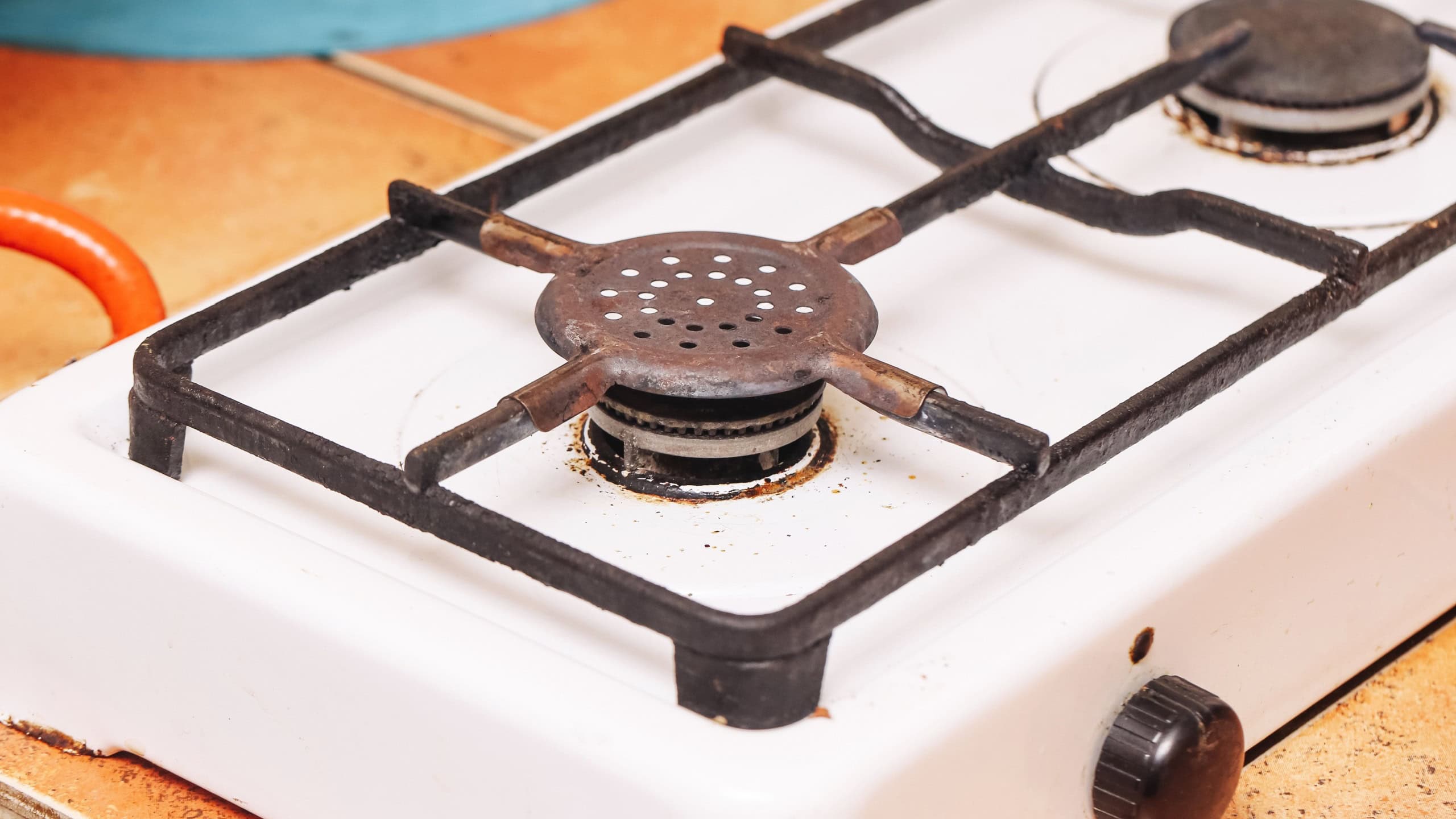 Old gas stove closeup. Rusty burner and dirty surface. Worn out kitchen appliance with stains. Household cooking equipment. Vintage gas hob used for preparing meals. Home interior detail concept.