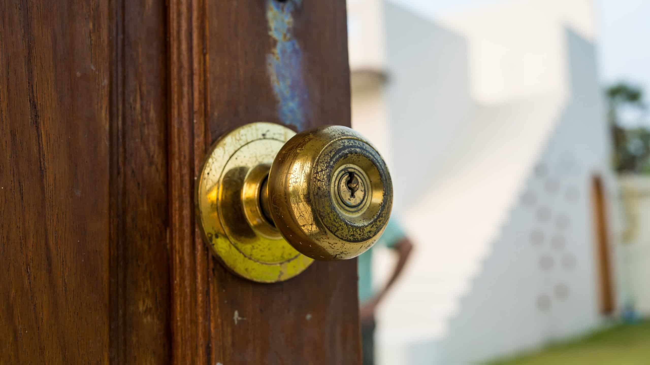Vintage door knob on weathered wooden door. A gold door knob