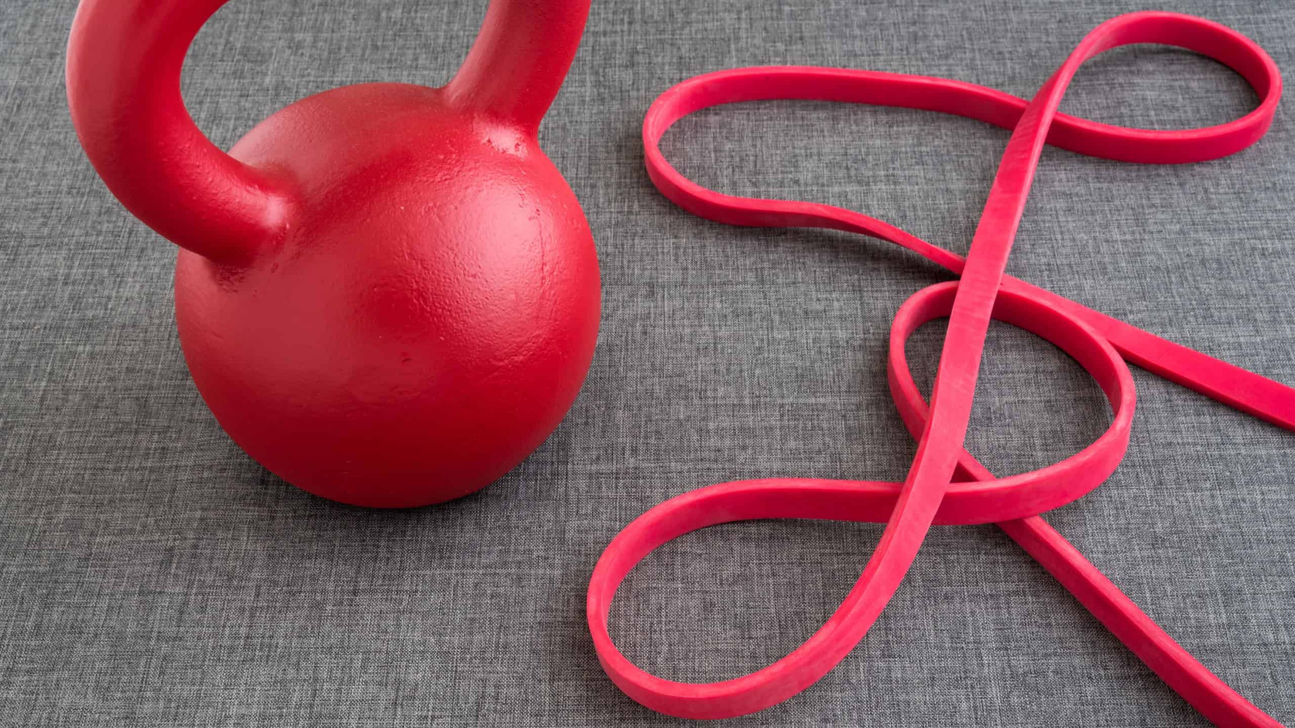 Red kettle bell and red resistance band on a gray background