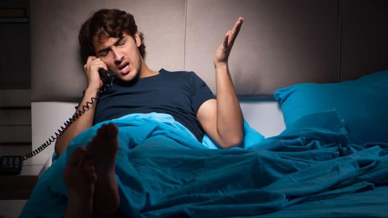 Young man talking on phone in bed