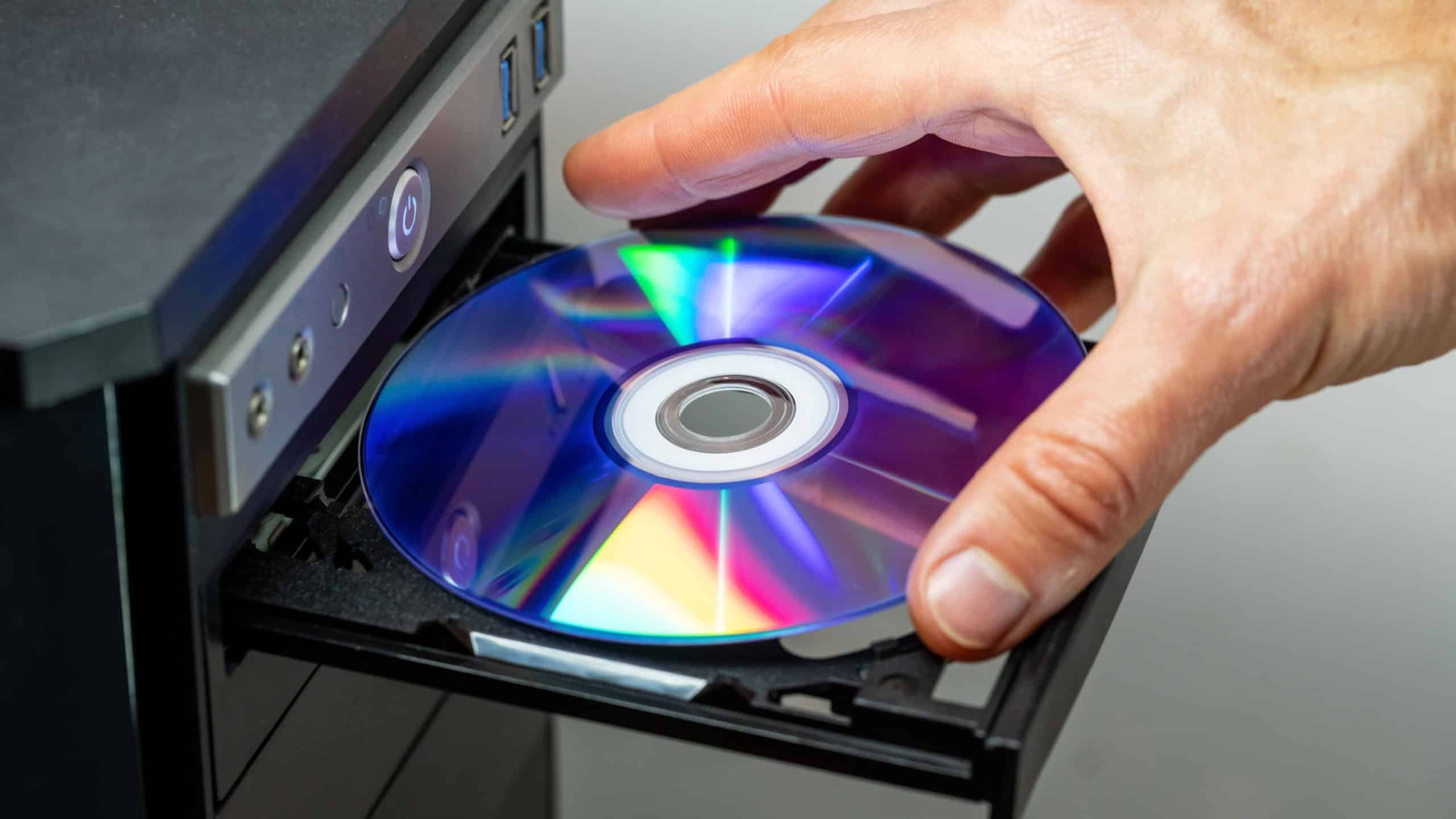 Hand inserting DVD into a computer. Closeup.