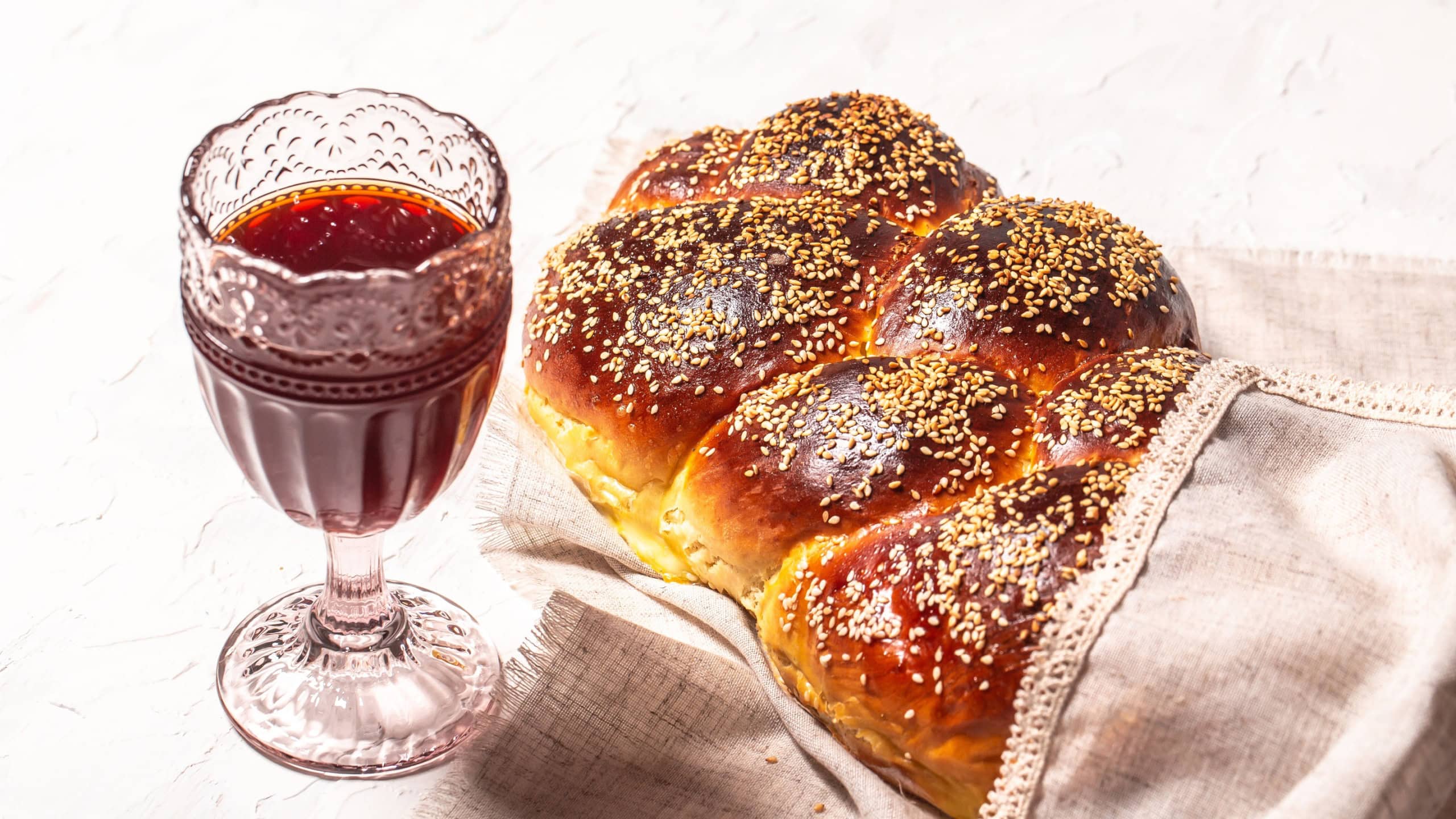 Shabbat or Sabbath kiddush ceremony. The concept of oriental cuisine. National Israel sweet fresh loaf of challah bread, glass of red kosher wine.