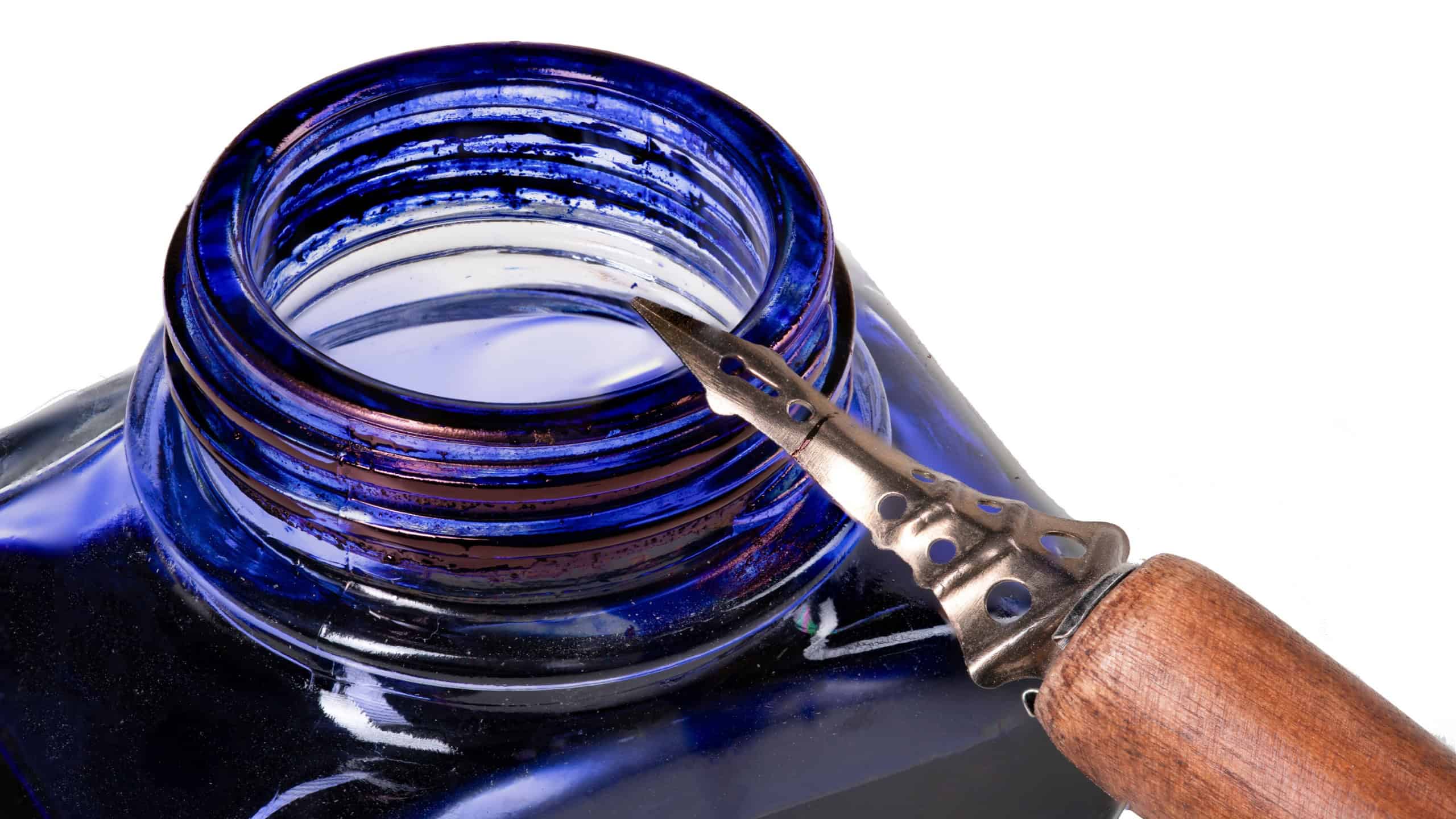 Metal nib for writing and calligraphy. A pen resting on a glass inkwell. Isolated background.