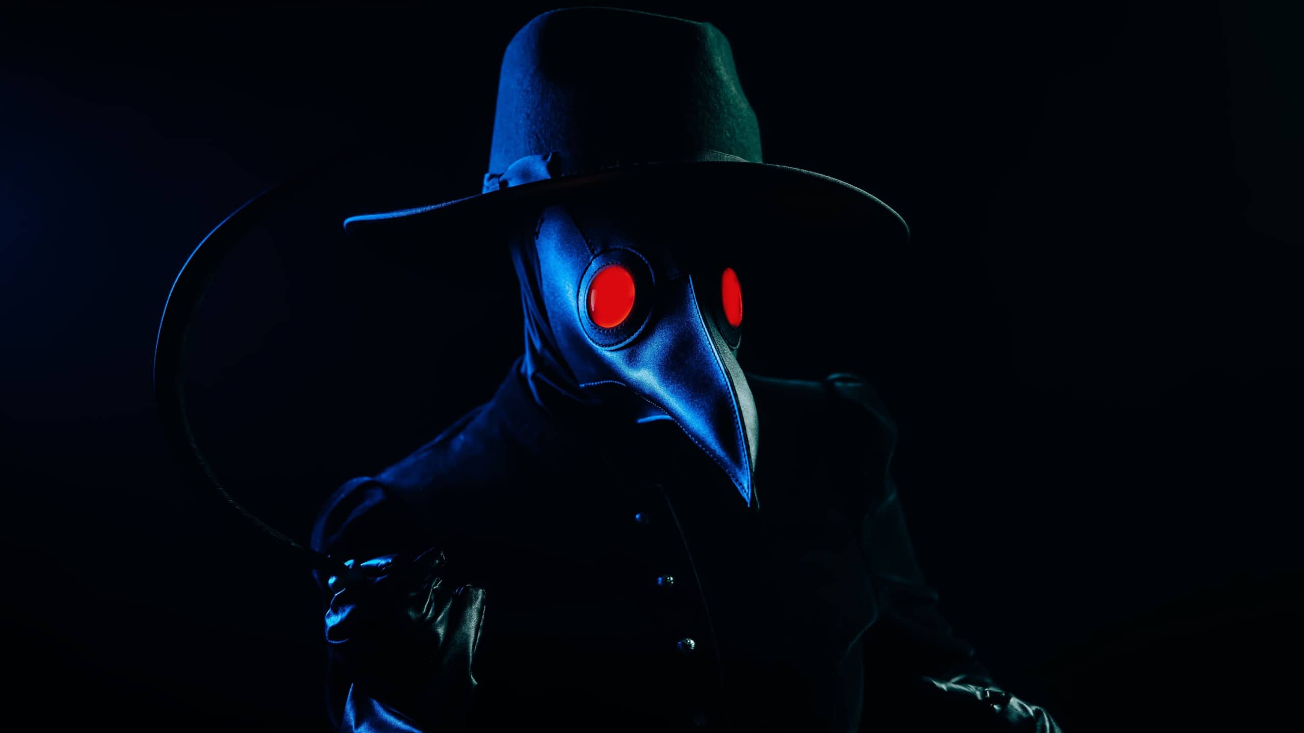 Plague doctor with sharp sickle on smoke black background. Creepy raven mask, halloween, historical terrible protection costume, mystical fantasy. Epidemic, death concept. High quality photo
