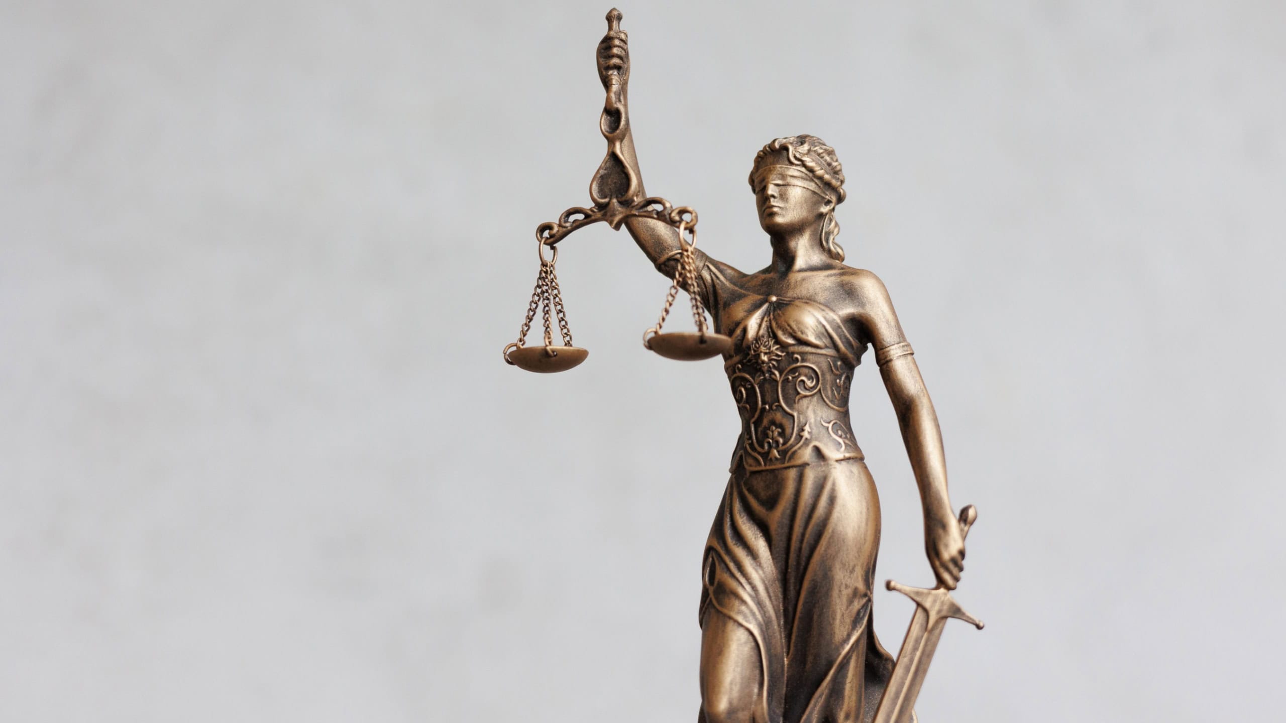themis goddess of justice statuette on light gray background. symbol of law with scales sword in hands. legal company or university of law and judicial structure. court acquittal of the verdict
