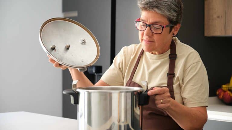 Mature Spanish woman opening a pressure cooker to cook cocido madrileño.