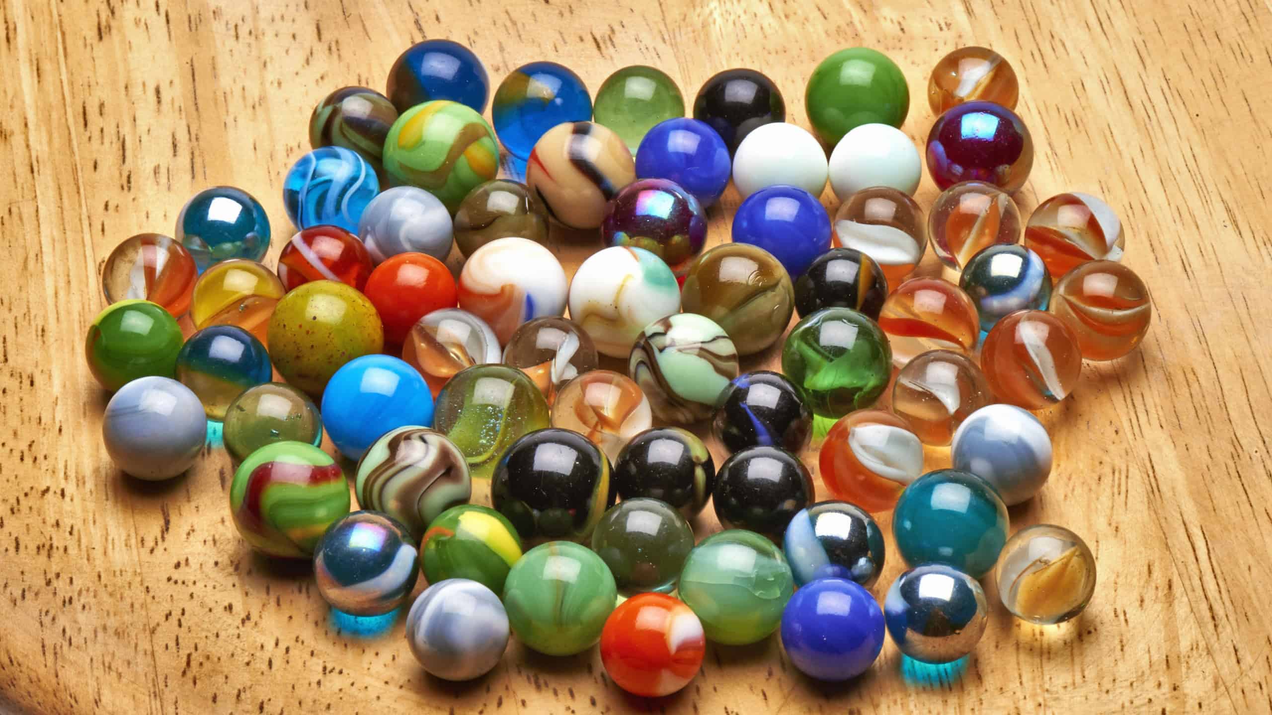 Lot of Multi colored Marbles on wooden board