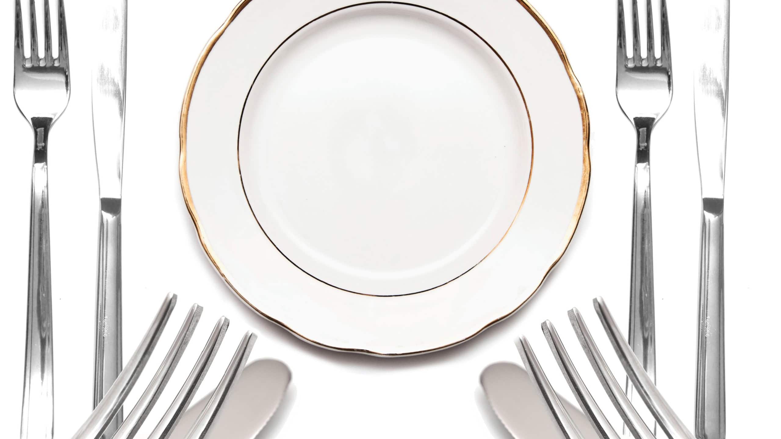 Knife, white plate and fork on a white background