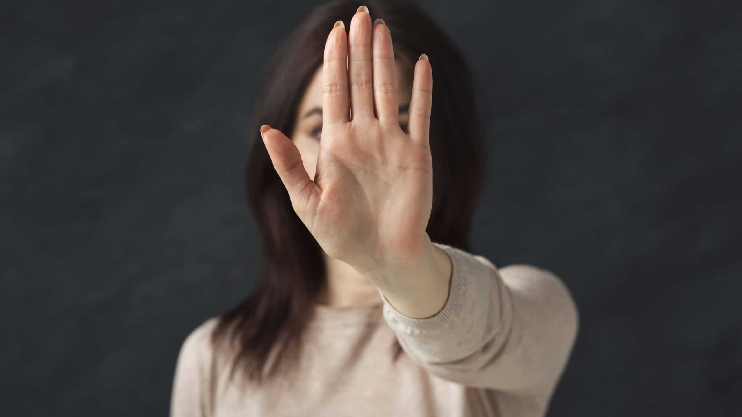 Young woman saying no. Girl denying proposal, making stop gesture with her hand. Studio shot, copy space
