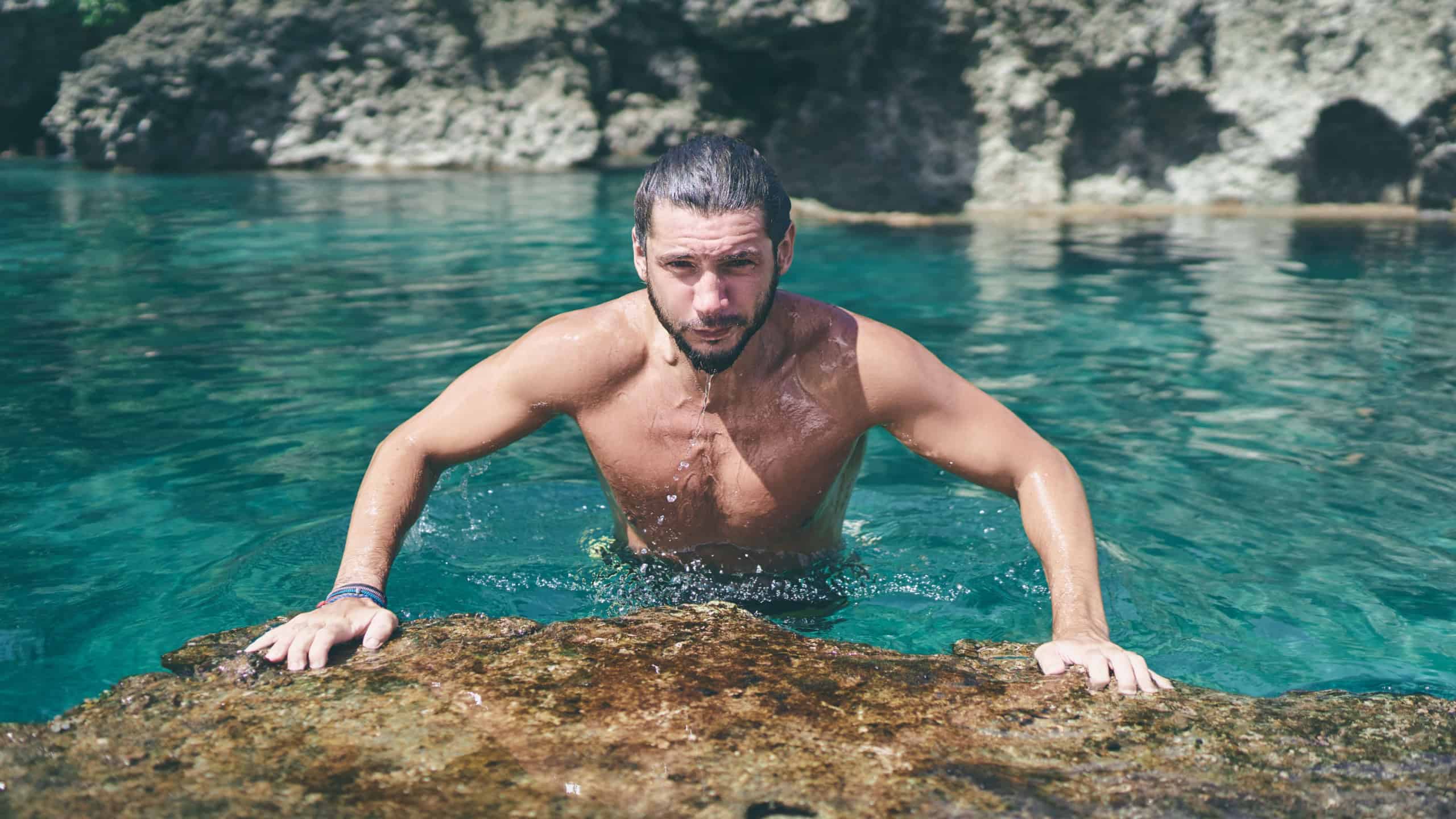Summer vacation. Young bearded man bathing at sea natural pool.