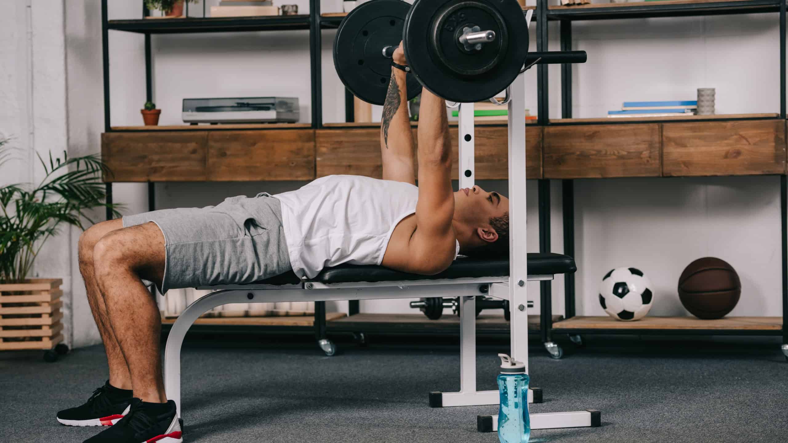 muscular mixed race man workout with barbell in home gym
