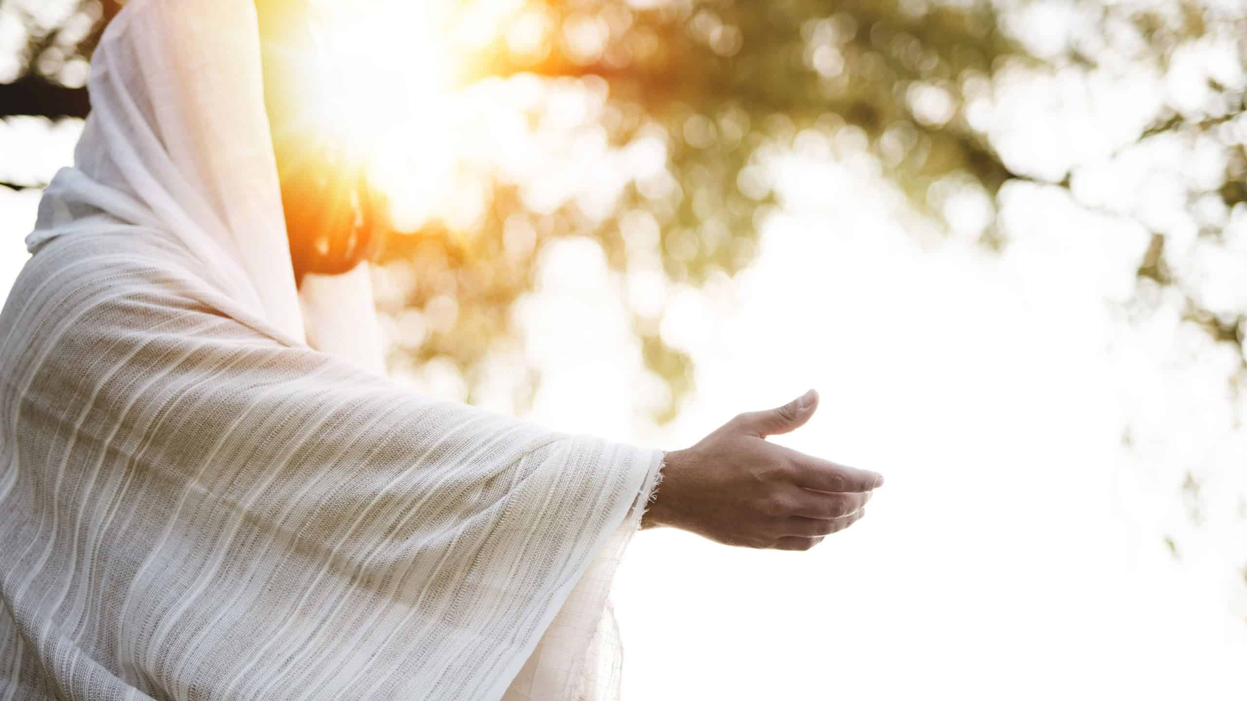 A biblical scene - of Jesus Christ landing a hand for help with the sun shining near his face