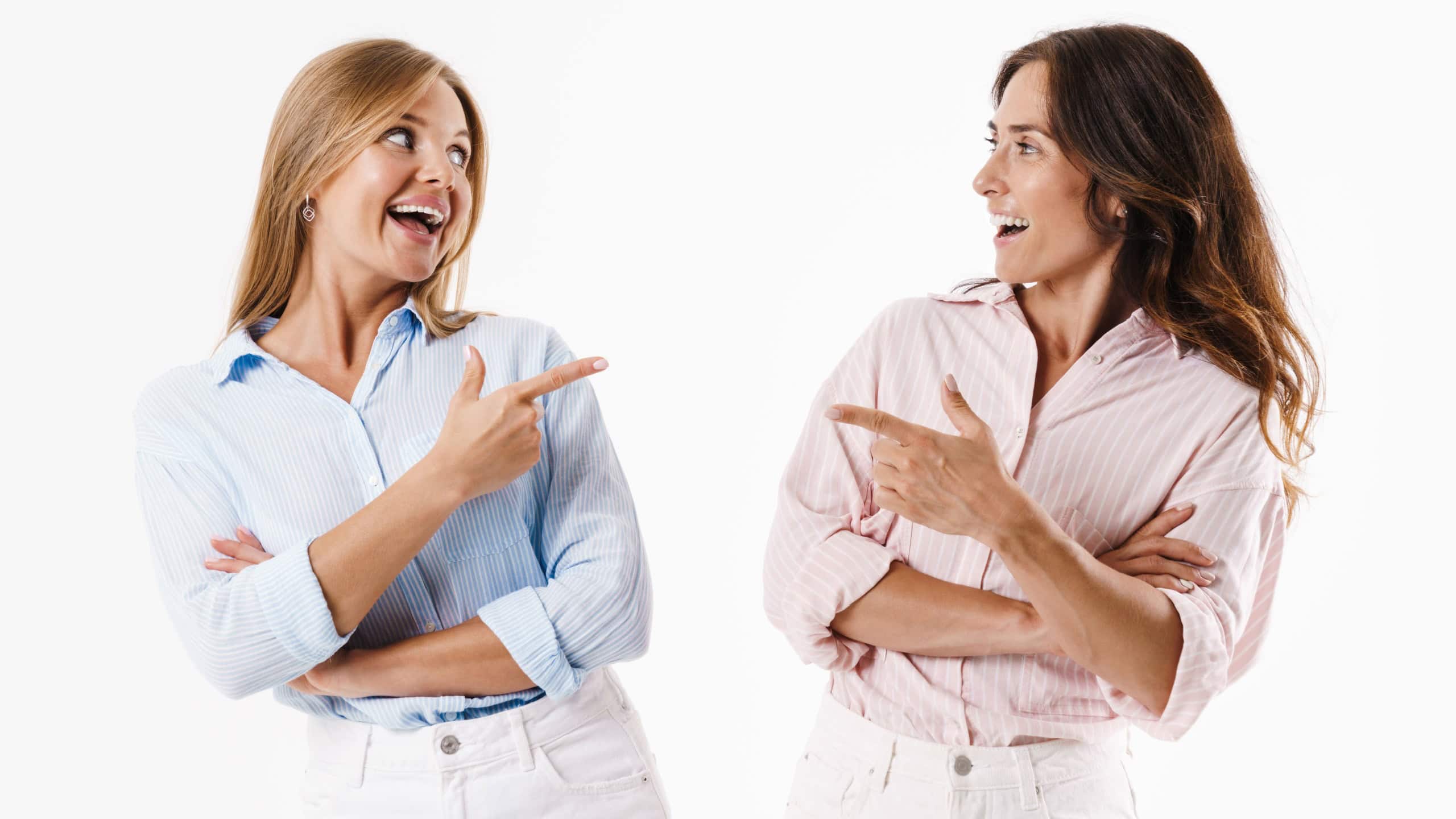 Image of joyful nice two women pointing fingers at each other and laughing isolated over white background