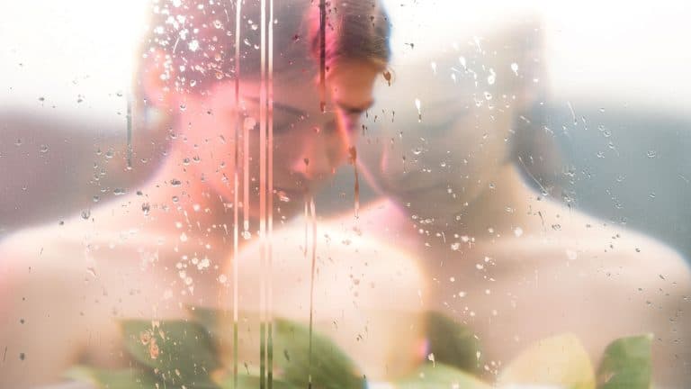 Nature portrait. Nostalgic melancholy. Sensual peaceful woman face blur silhouette with green leaves behind steamed wet glass double exposure effect. Freshness purity. Feminine beauty.