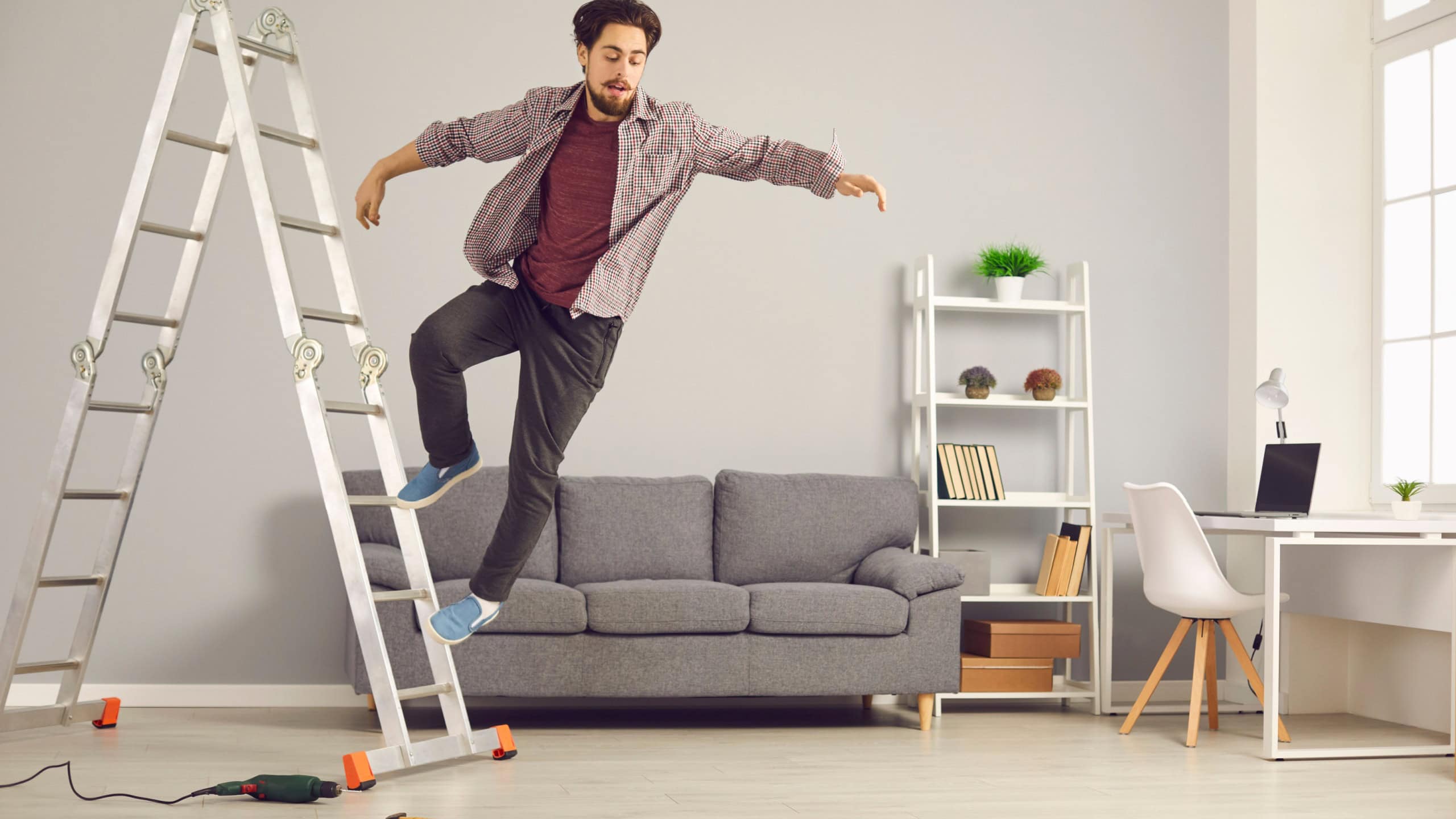Unlucky young man has slipped from ladder while doing repairs and renovating house and is falling down on floor. Concept of getting hurt and injured in dangerous domestic accidents at home