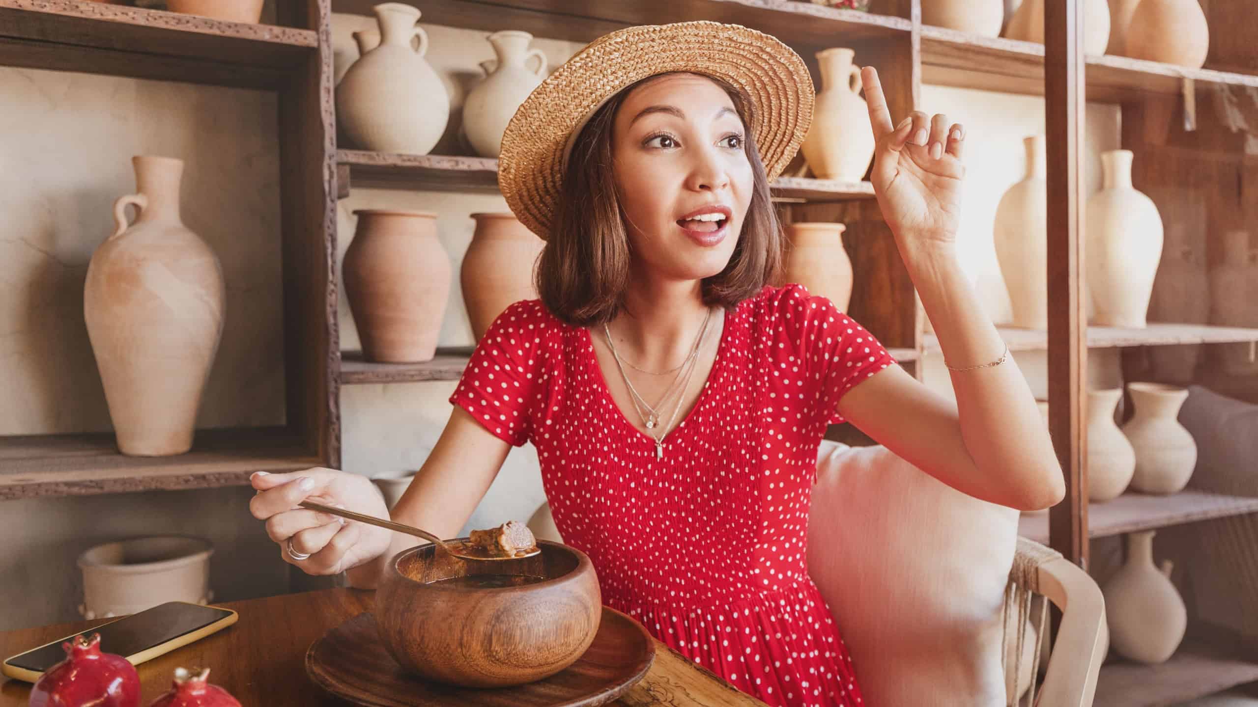 The woman raised her hand and calls the waiter to ask a question about the quality of lunch in the restaurant
