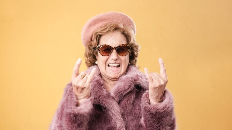Stylish elderly woman showing rock and roll gesture