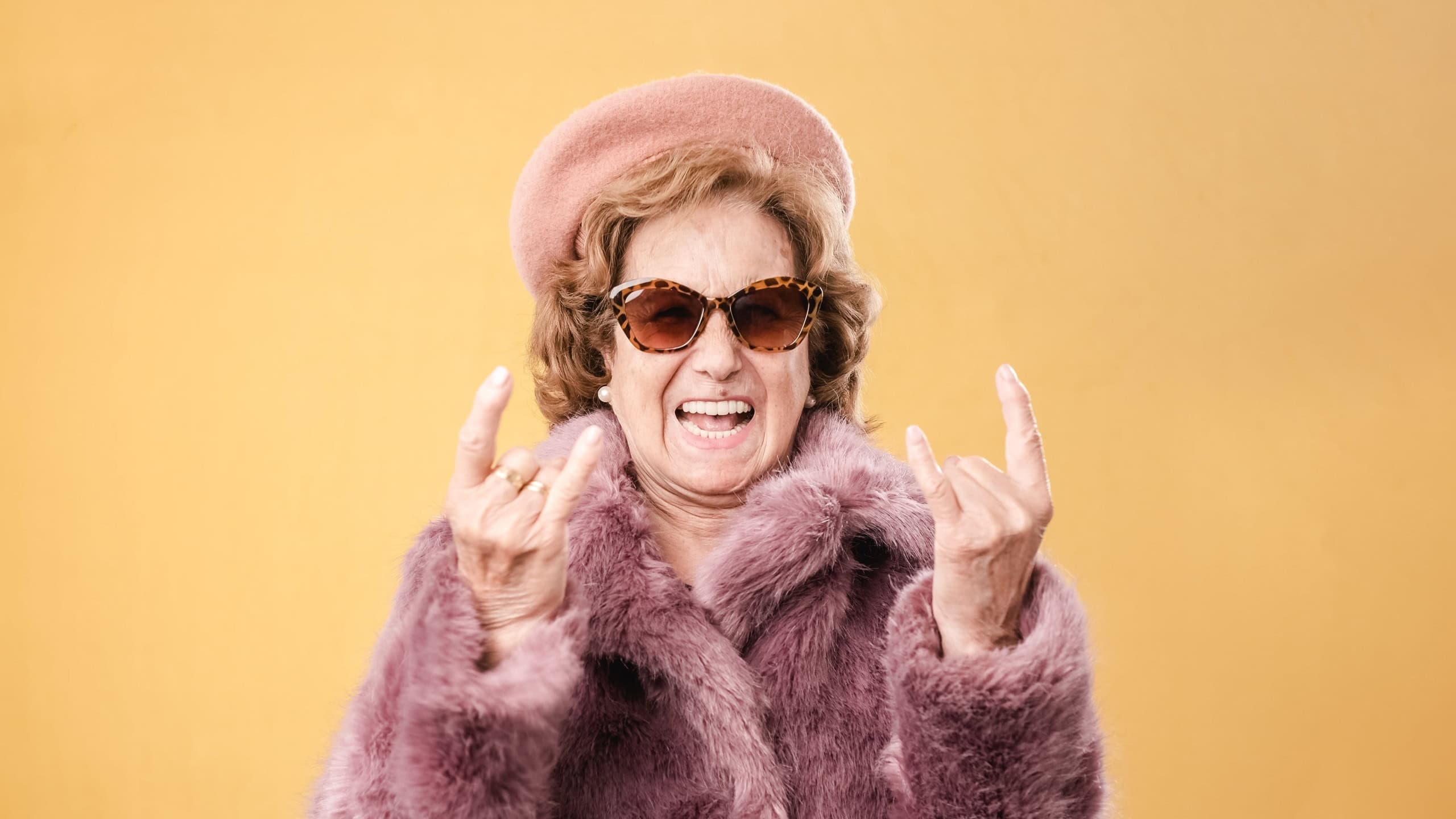 Stylish elderly woman showing rock and roll gesture