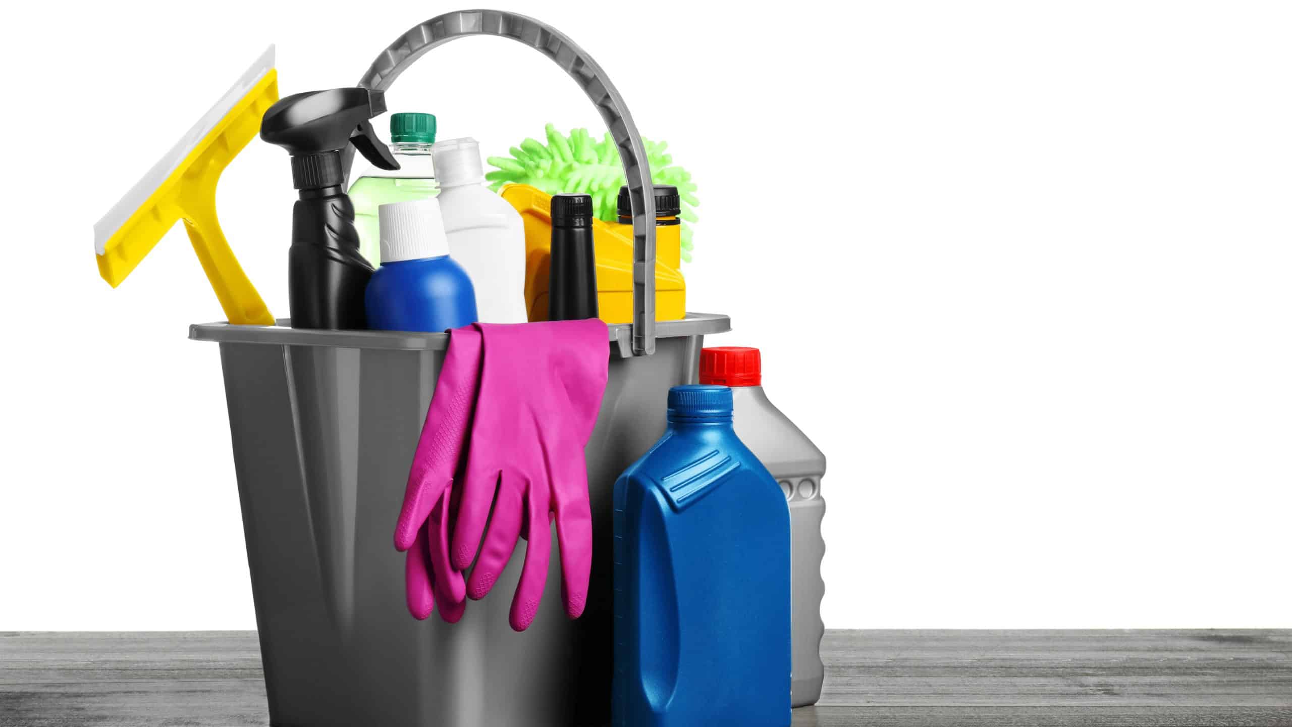 Grey bucket with car care products on wooden table against white background