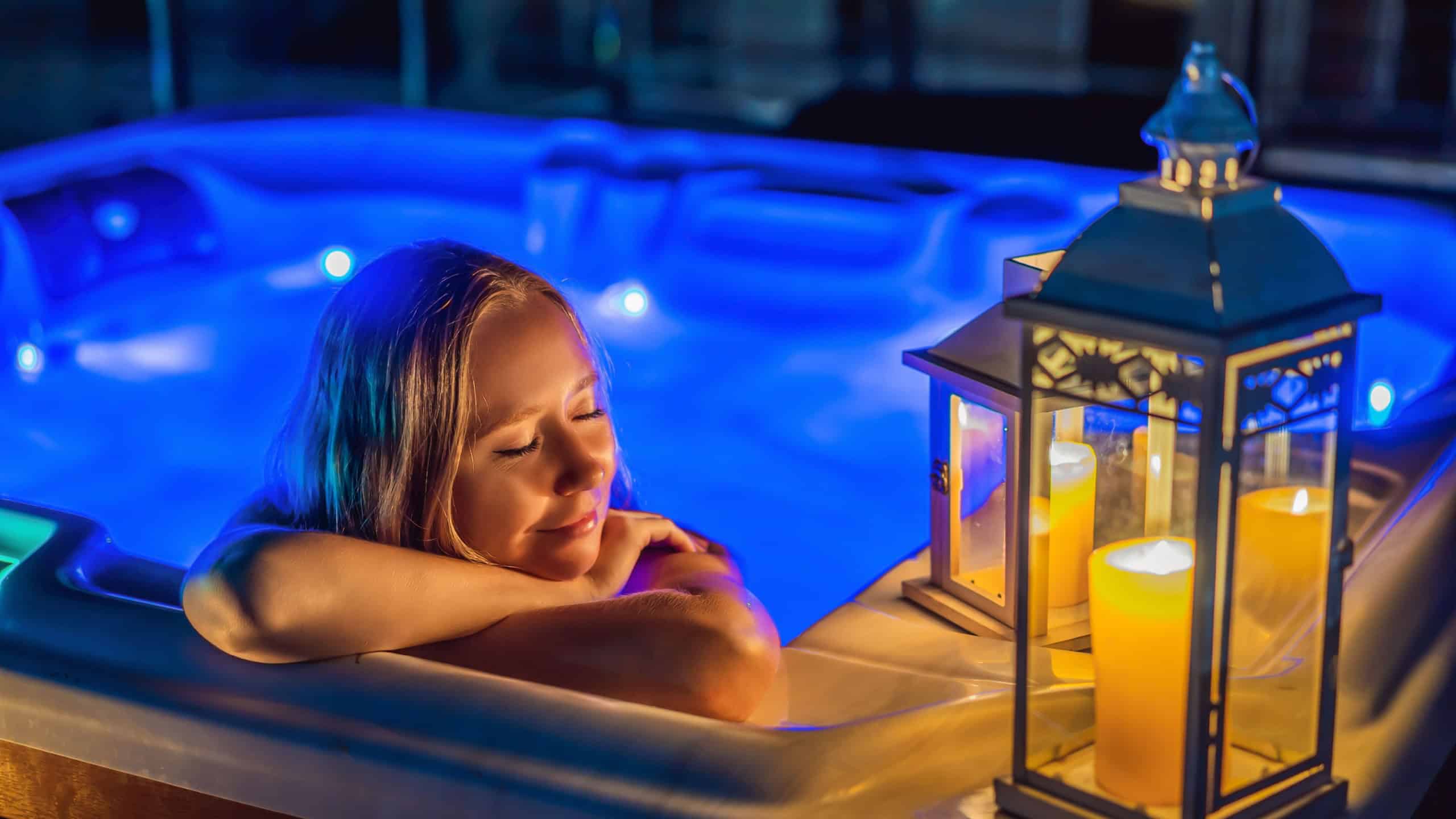 Portrait of young carefree happy smiling woman relaxing at hot tub at night during enjoying happy traveling moment vacation. Life against the background of green big mountains