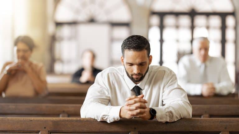 Church, prayer and man praying to God, worship or religion in cathedral. Faith, spiritual and christian community in chapel or sanctuary worshipping Jesus, holy praise or trust and hope in Christ.