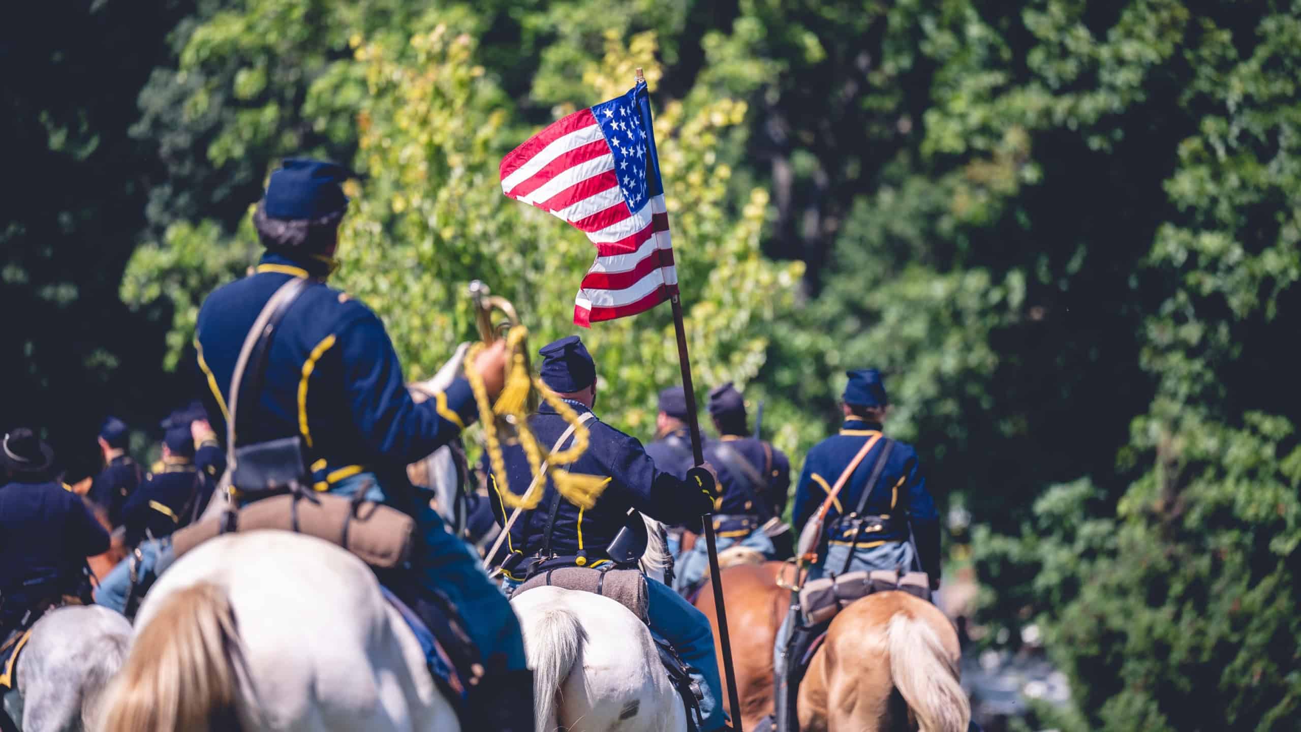 JACKSON, UNITED STATES - Sep 21, 2022: The soldiers with horses and the flag of America during military performance in the Civil war reenactment in Jackson city, Michigan, USA