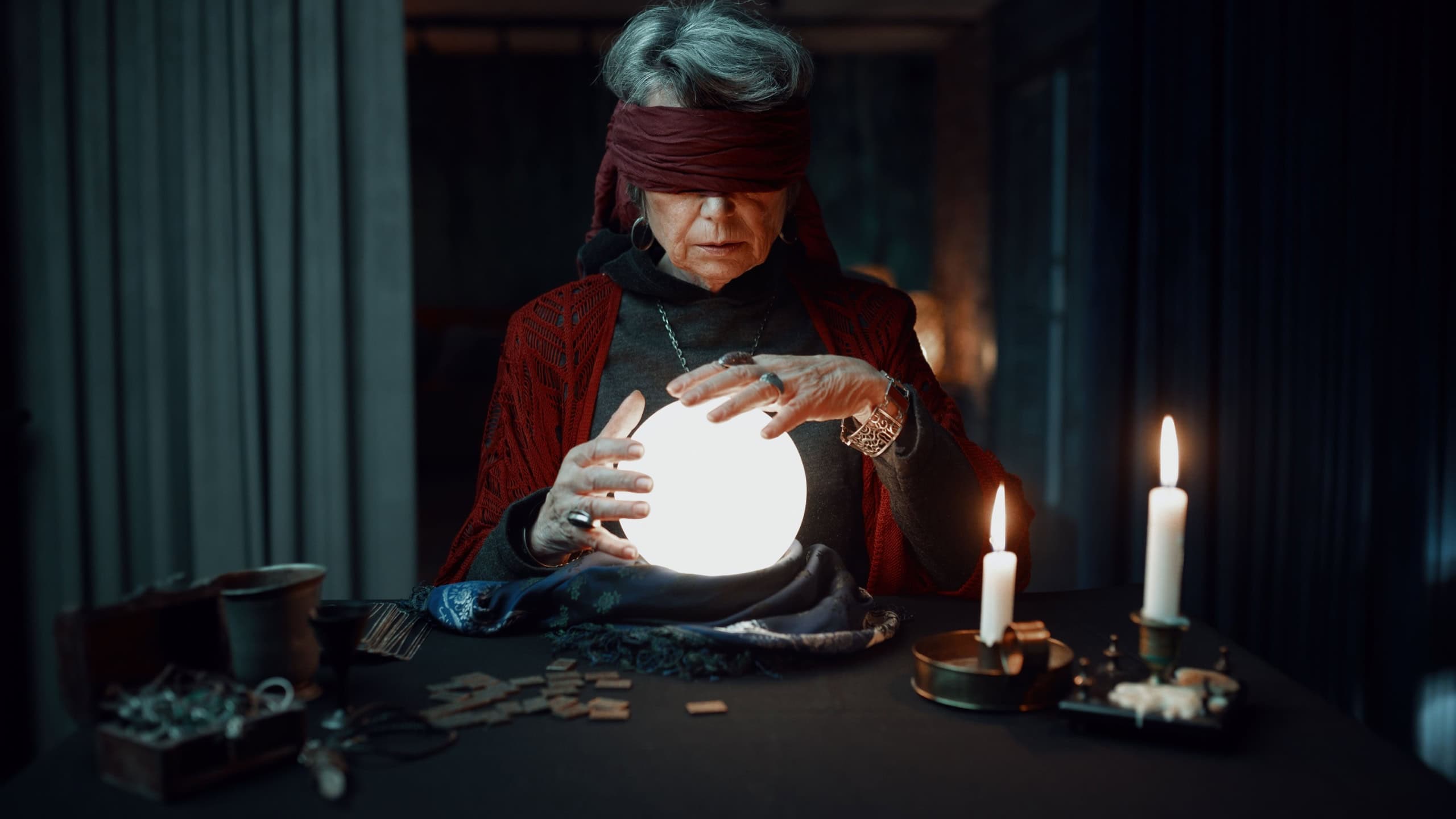 Blindfolded fortune teller using glowing crystal ball for future reading