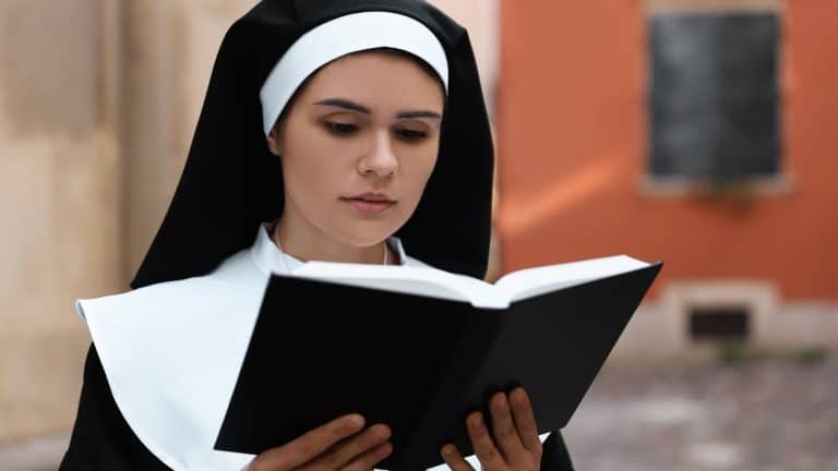 Young nun reading Bible near building outdoors
