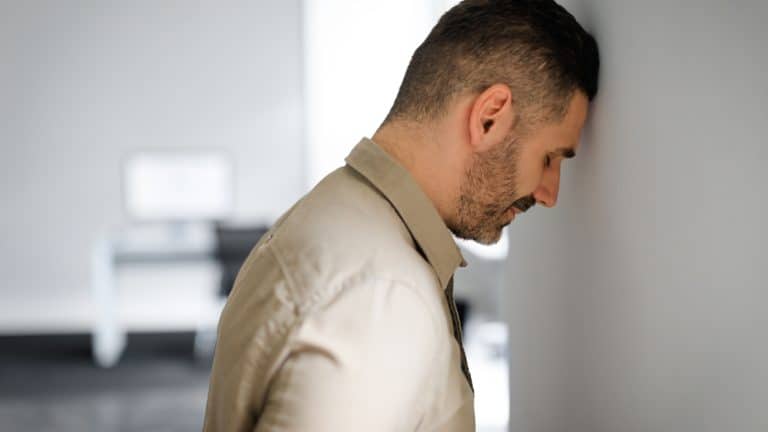 Upset middle aged businessman banging his head against wall in despair looking stressed, having problems at work. Business failure, unsuccessful negotiations, failed job interview concept