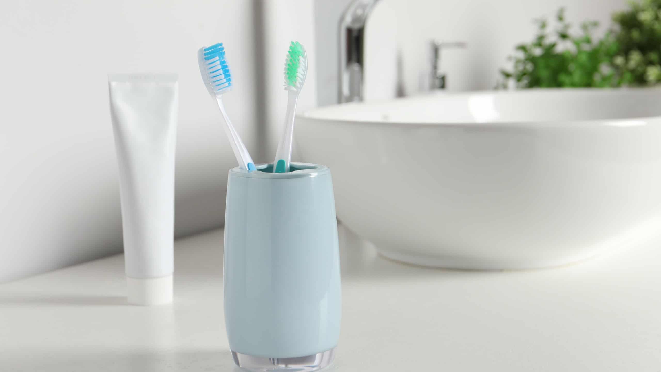Plastic toothbrushes on white countertop in bathroom, space for text