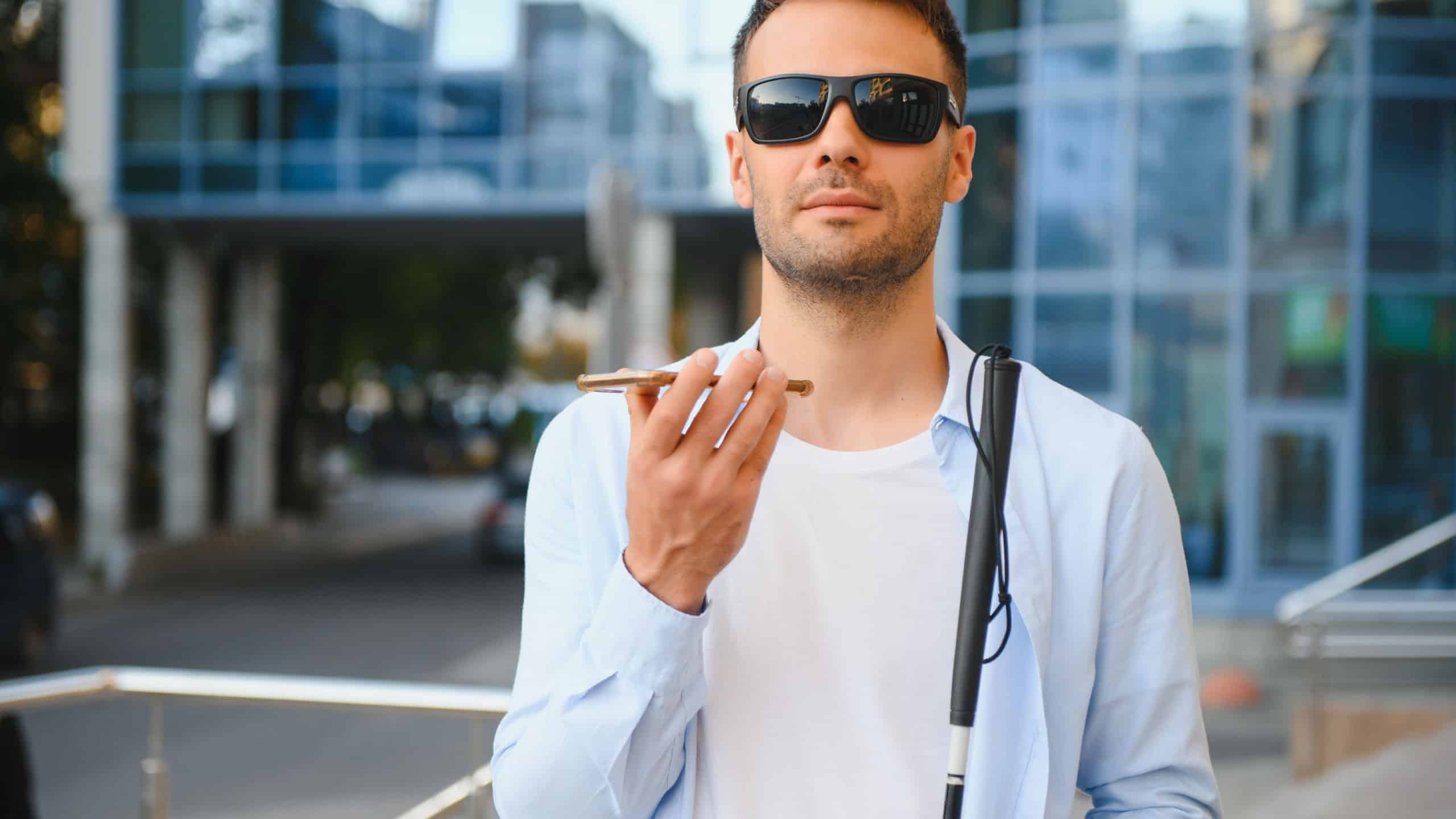 Young blinded man using phone and sending voice message.
