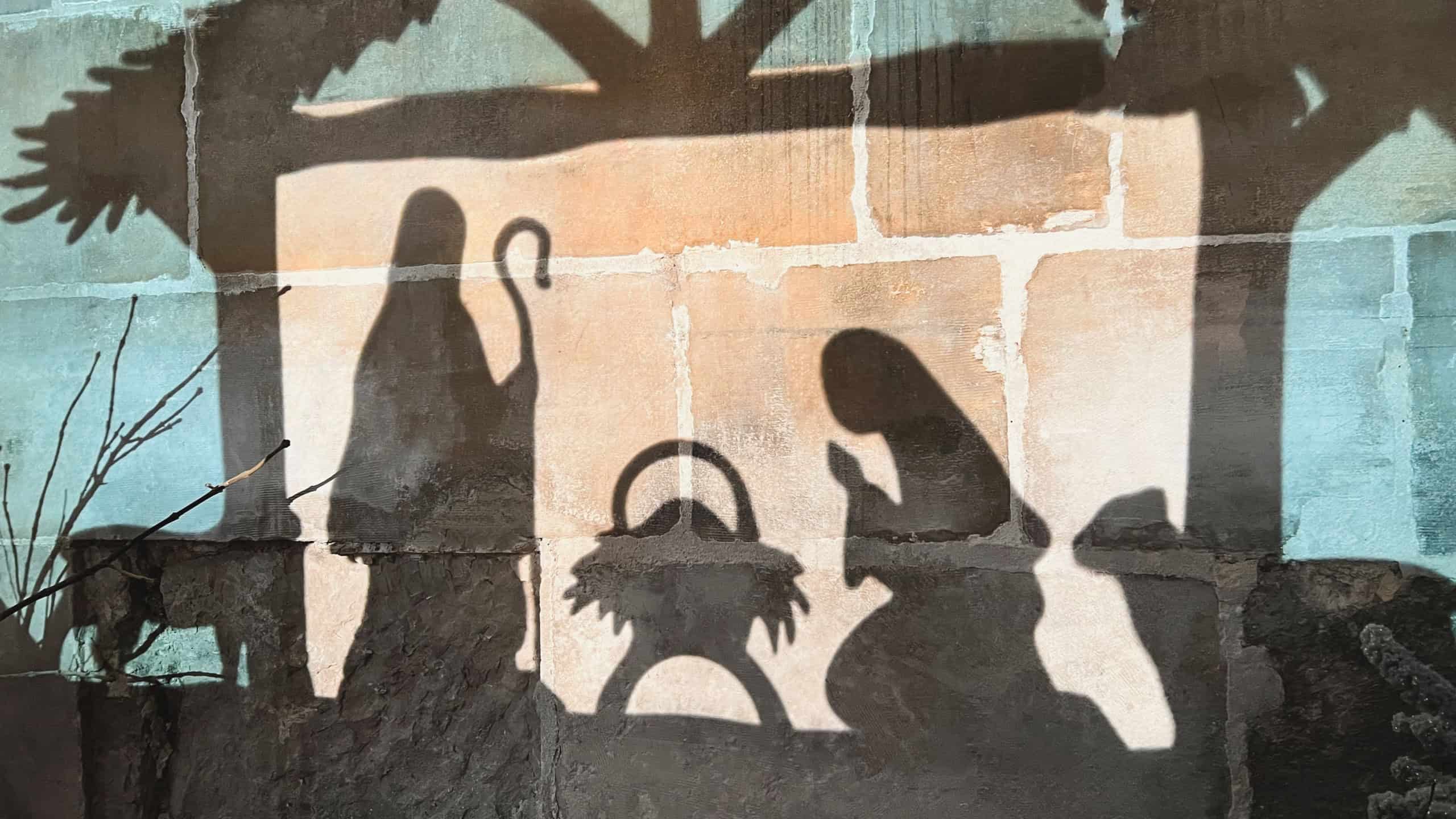 Reflection on the wall of christmas creche with Joseph Mary and small Jesus in a crib