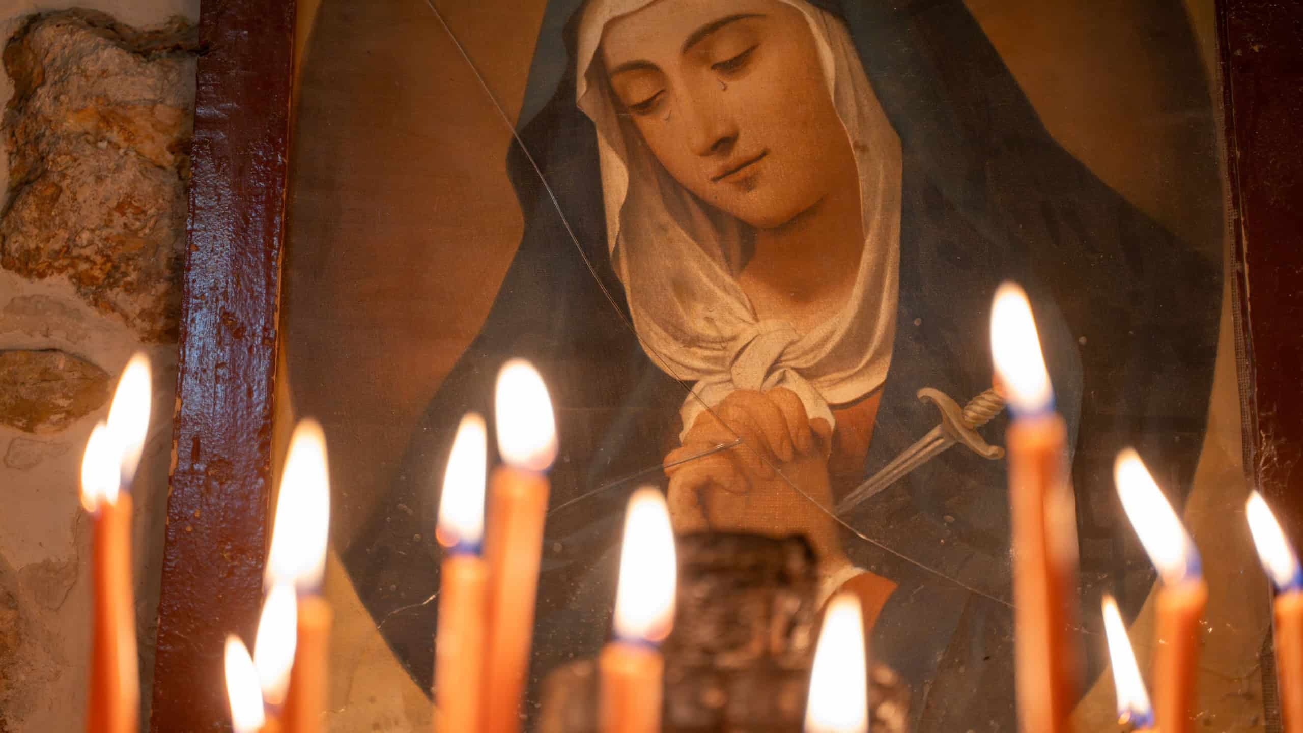 Burning candles in the church and Saint Mary painting.