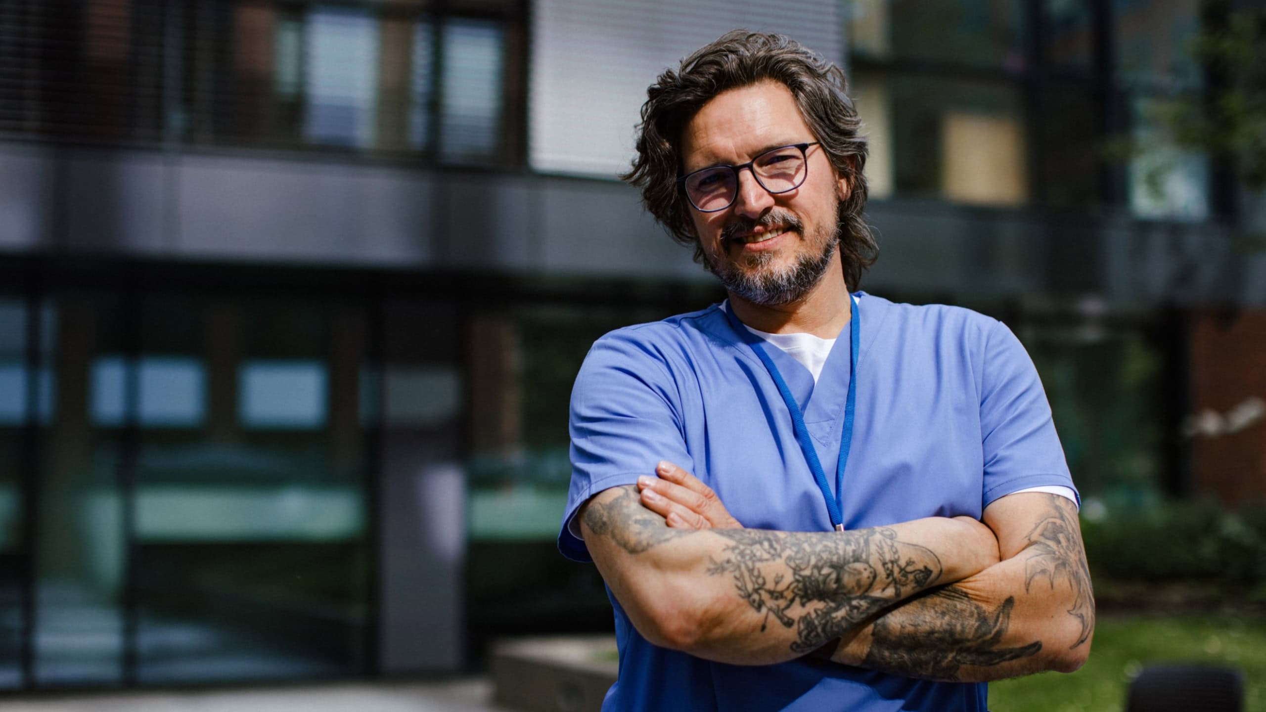 Portrait of handsome doctor in uniform outdoors. Work-life balance of healthcare worker.