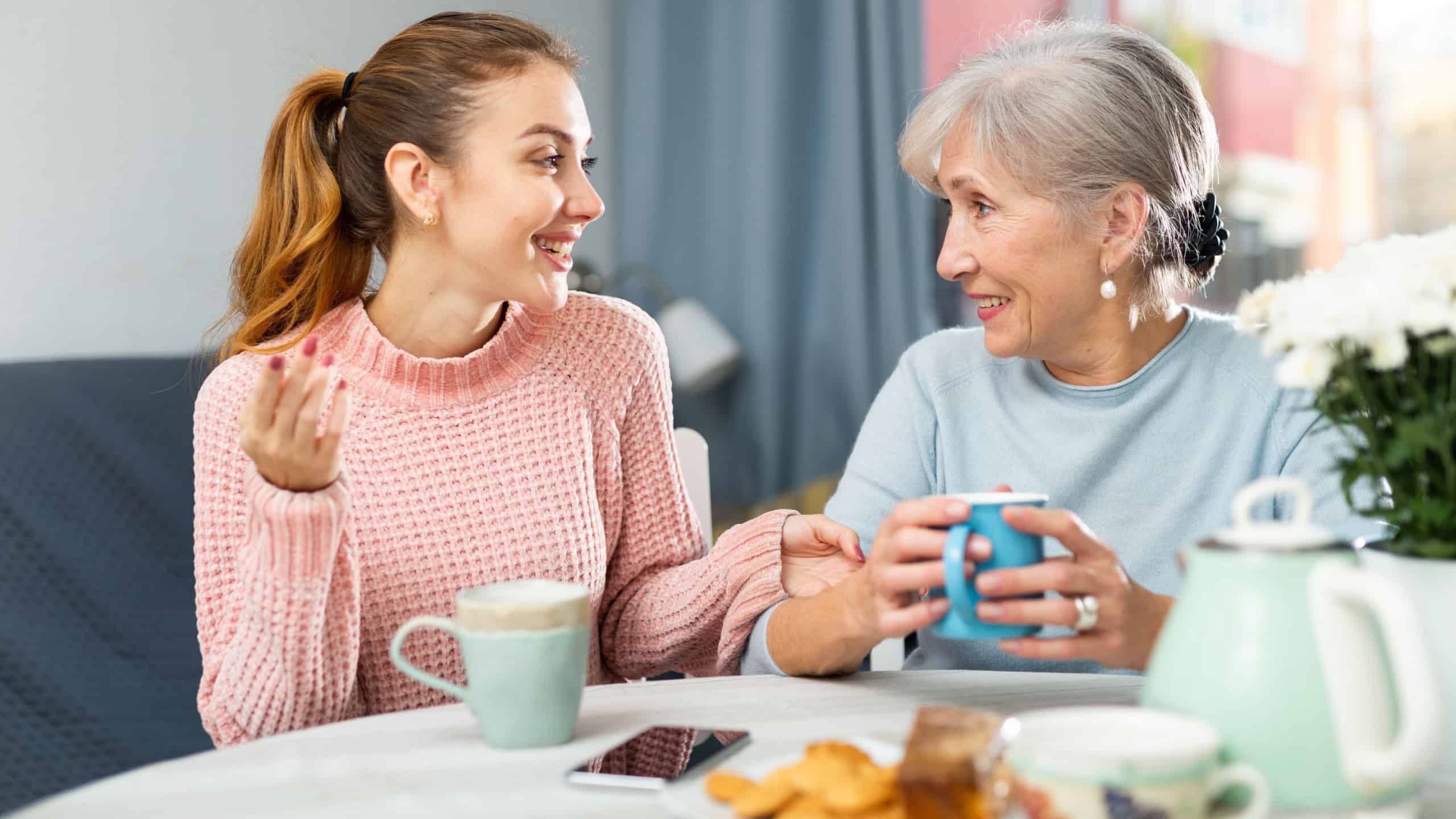 Grandchild and her grandma laughing while reading a book together.