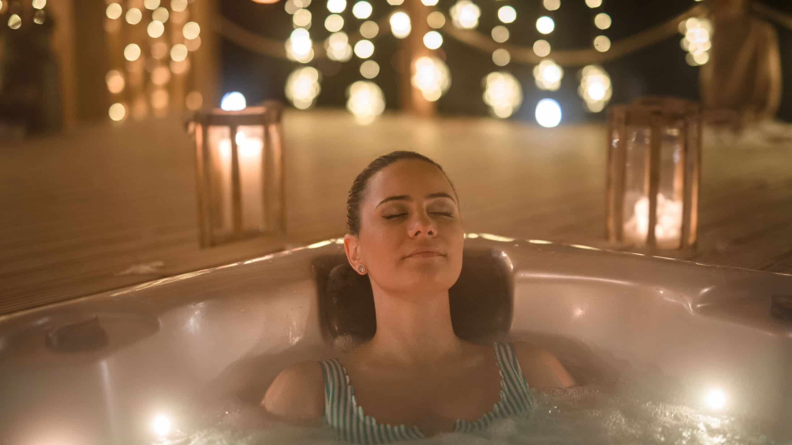 Relaxed woman in hot tub with closed eyes. Single woman celebrating Valentine's Day alone.