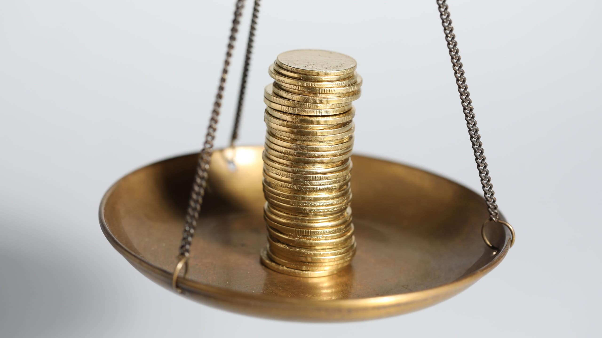 Many coins on scales against light grey background, closeup