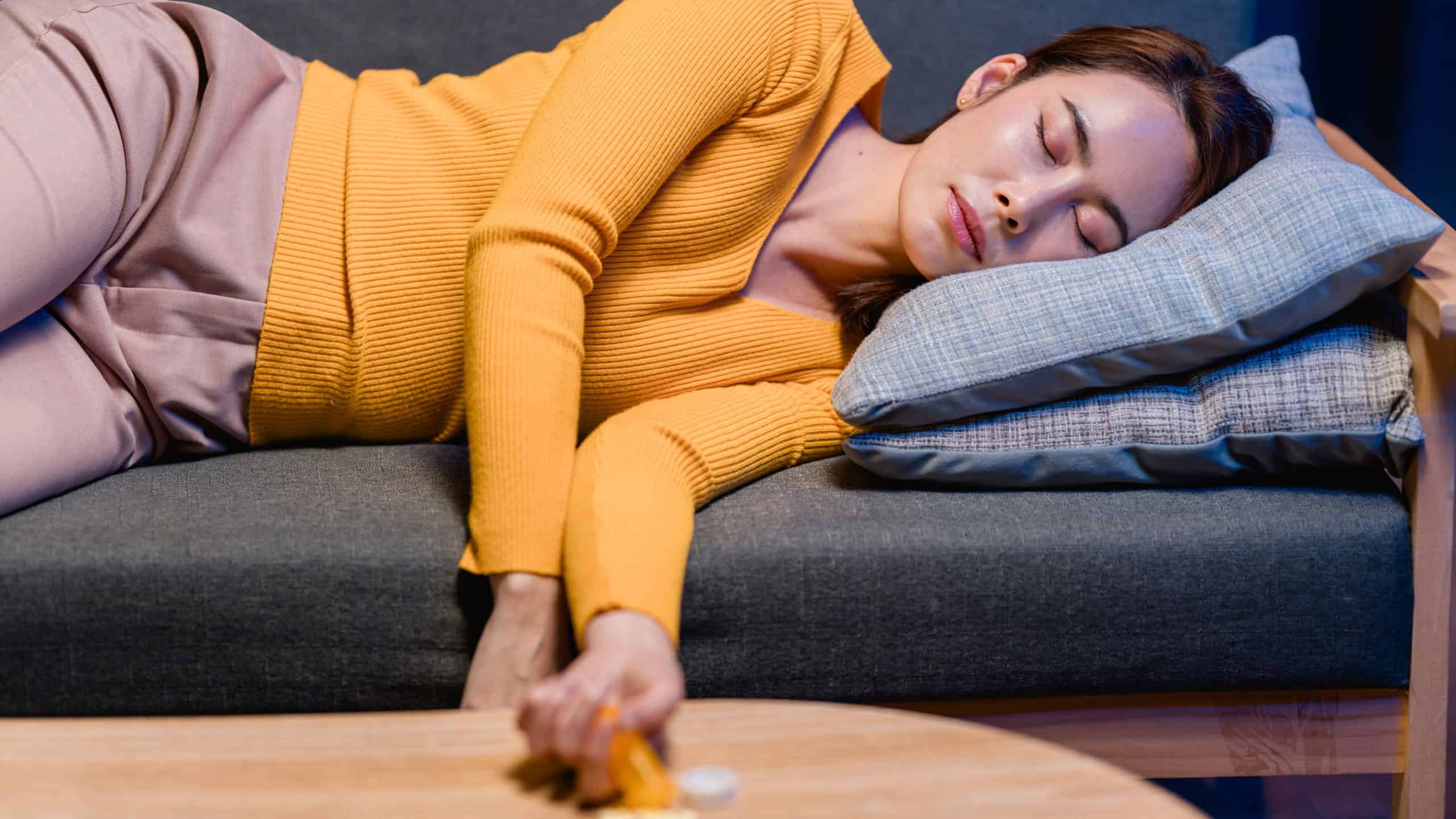 A young Asian woman is sleeping on the couch after taking medication. Overdose concept about Mental health awareness. She looks exhausted and needs rest.