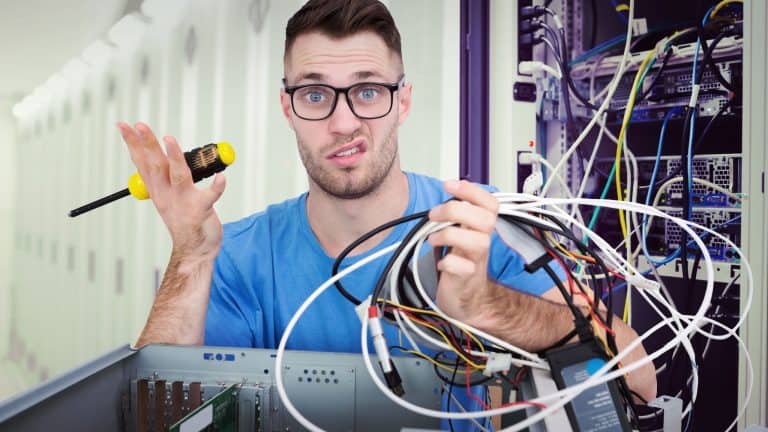 Portrait of confused it professional with screw driver and cables