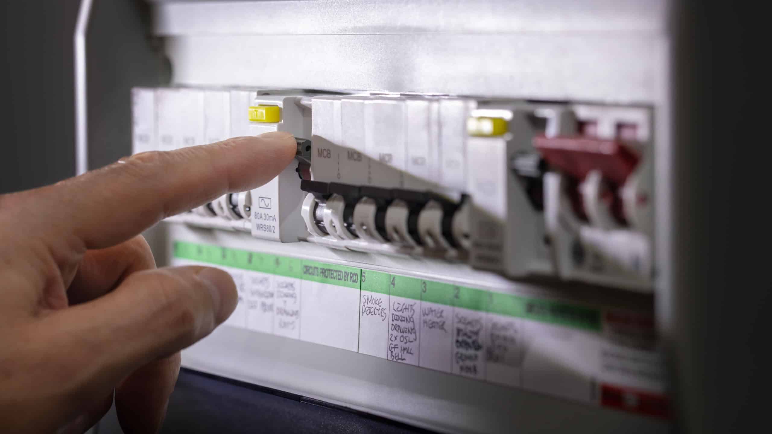 Electricity power outage emergency turning on or off circuit breaker on electrical fuse board with flashlight