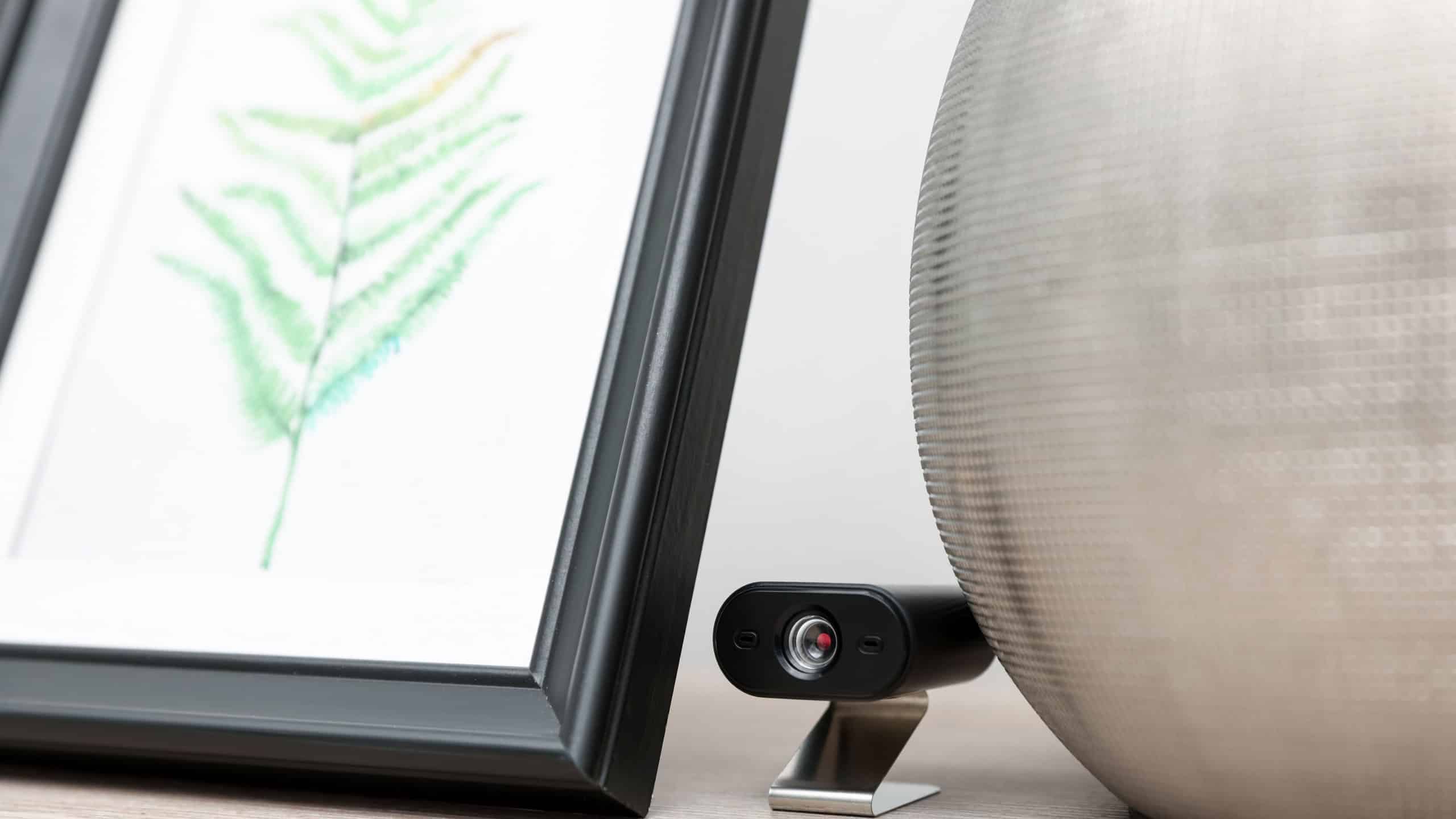 Hidden spy camera behind picture on shelf indoors, closeup