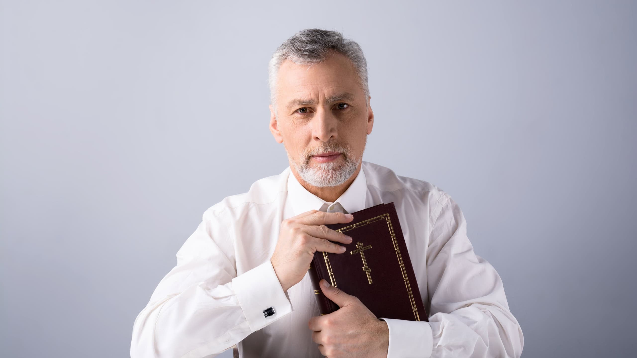 Old man looking at camera and holding Bible