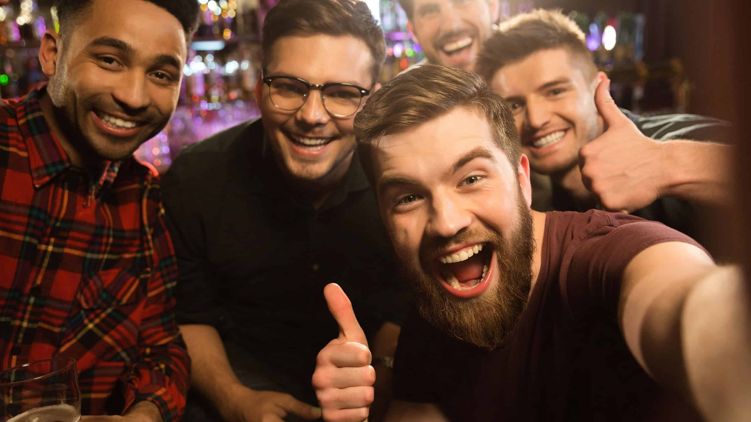Cheerful old friends having fun by taking selfie and drinking draft beer in pub