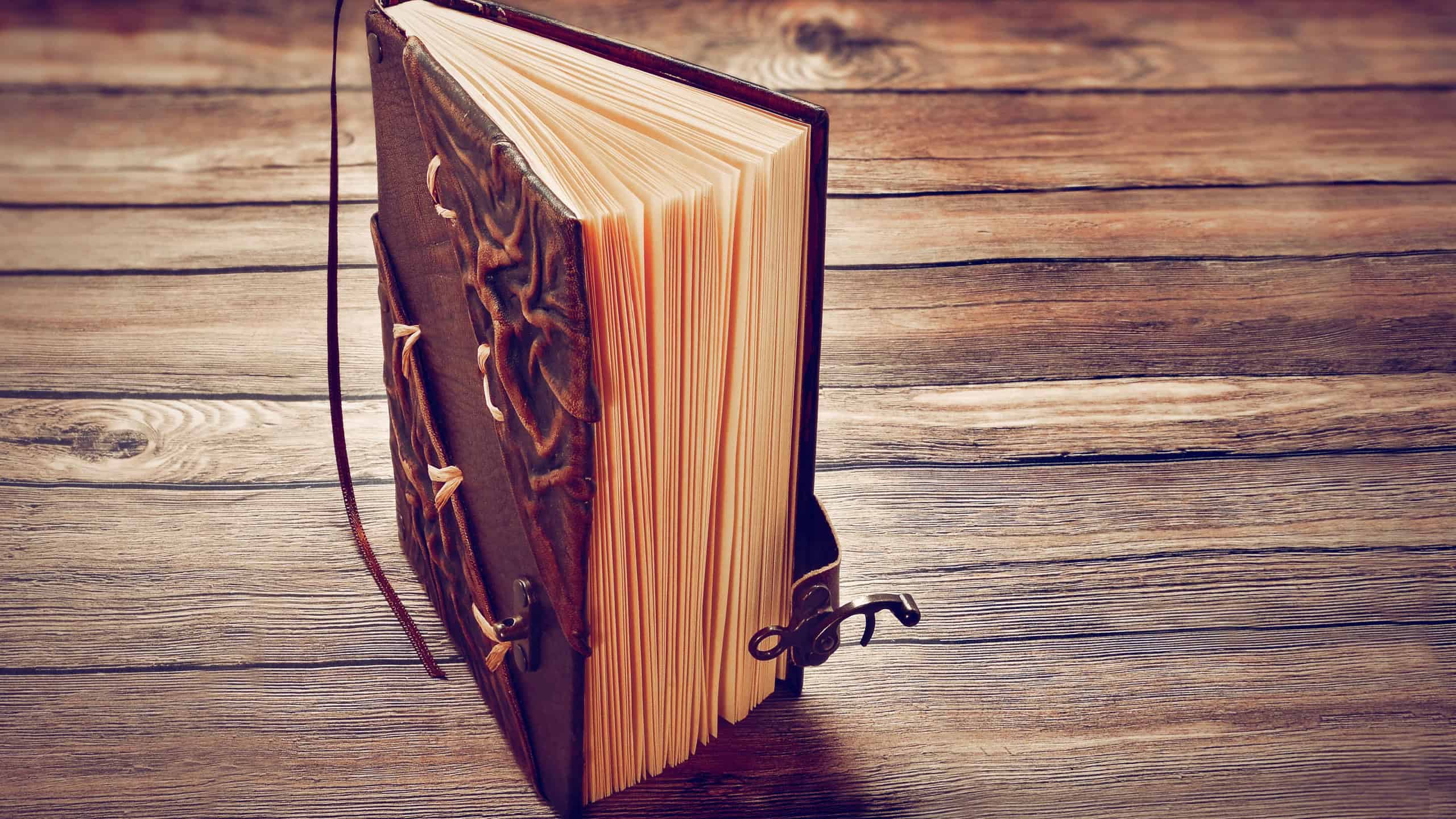 An empty, slightly open book standing on a wooden dark table. Leather cover with lock. With copy space. Toned. Vintage.