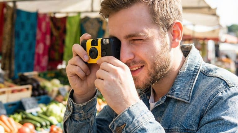 young caucasian man using a disposable camera