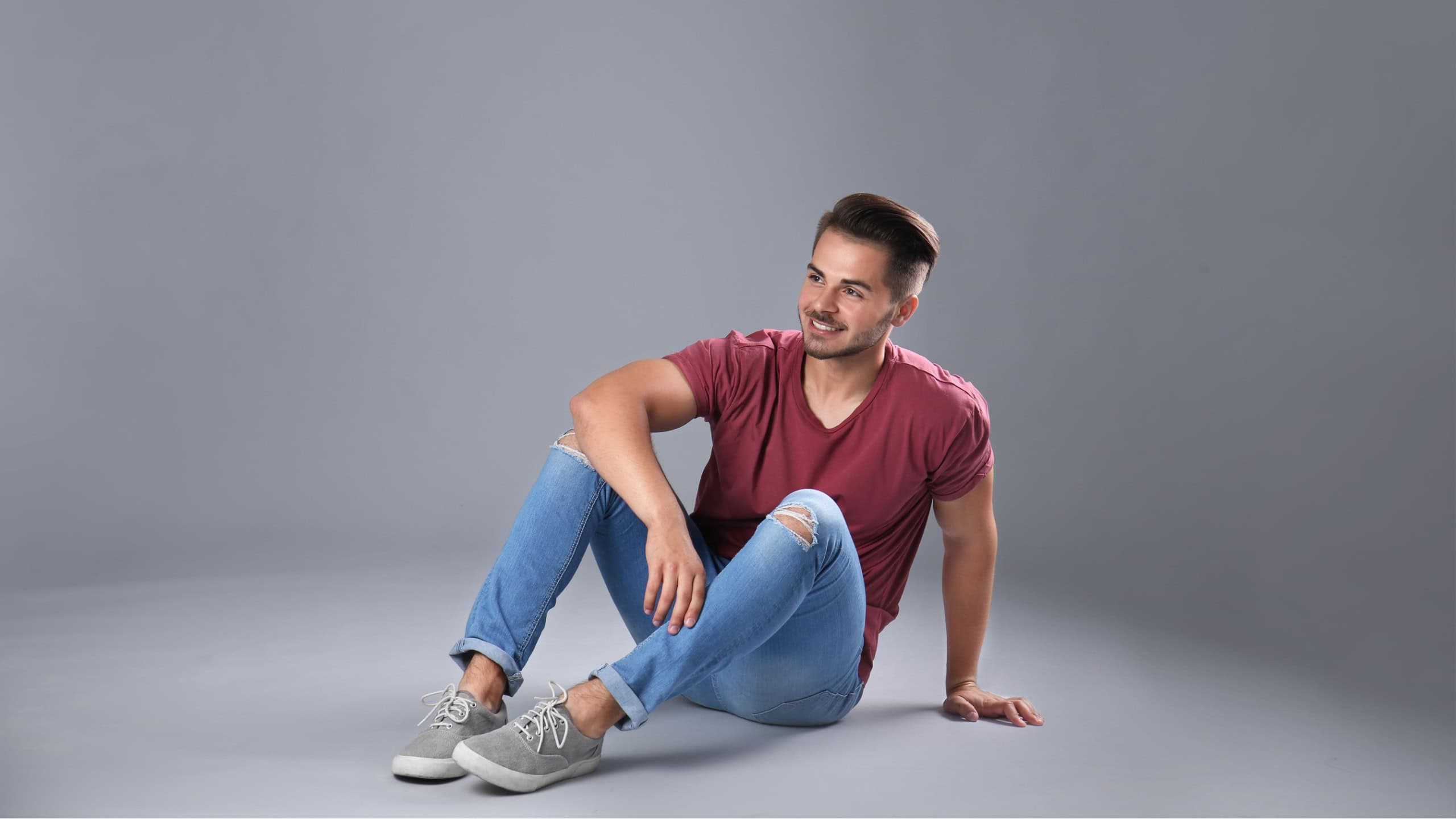 Young man in stylish jeans on grey background