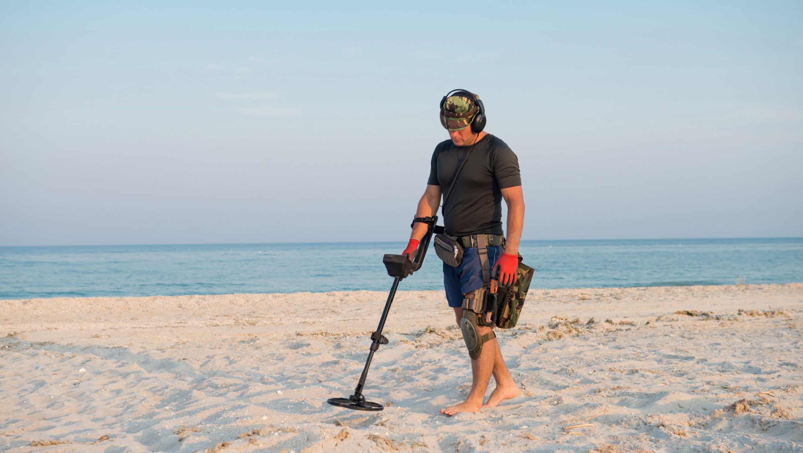 Man with a metal detector on a sea sandy beach