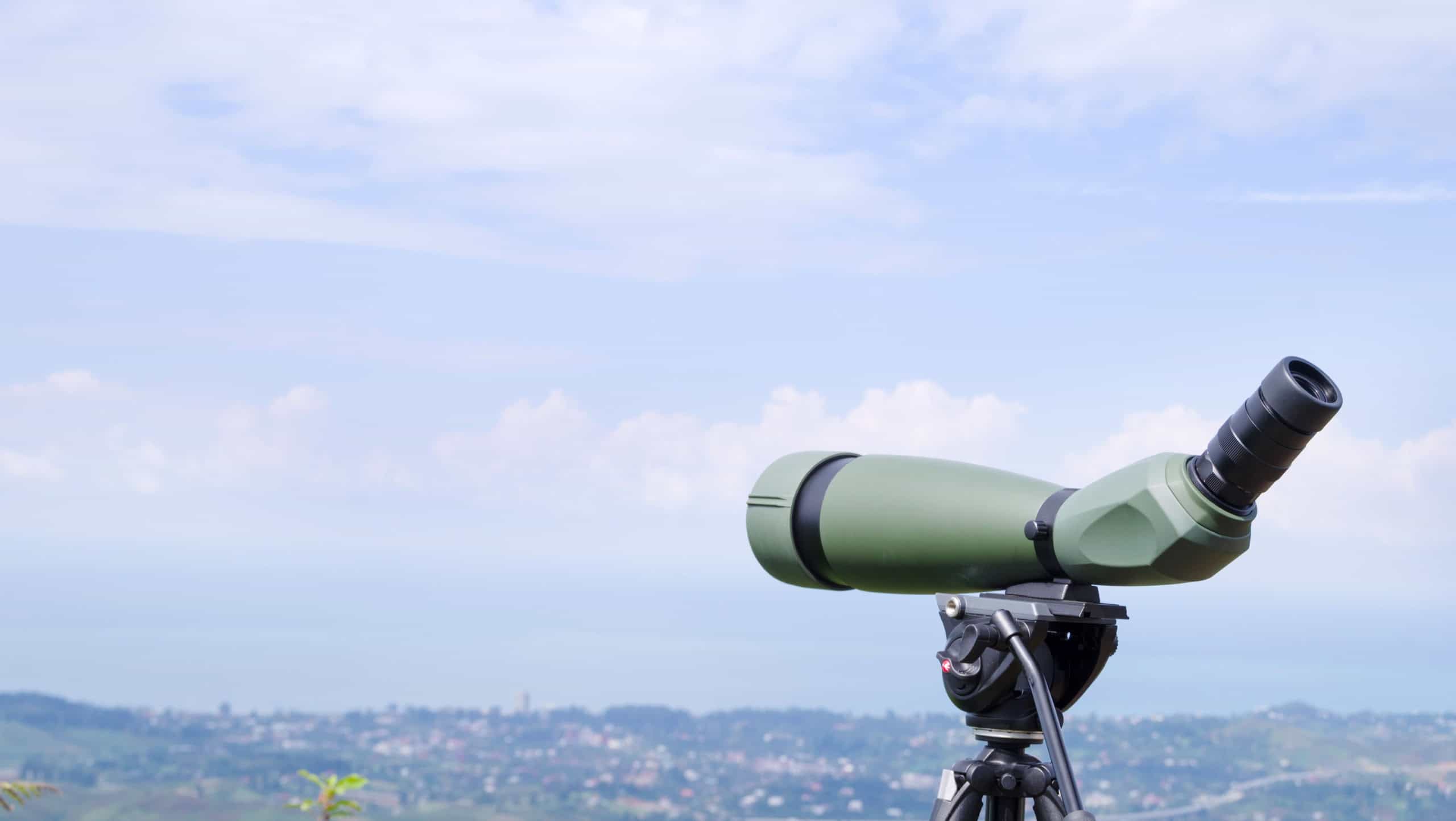 Green spotting scope or monocular at mountain top against the background of a mountain landscape in summer day. Observation of birds, birdwatching